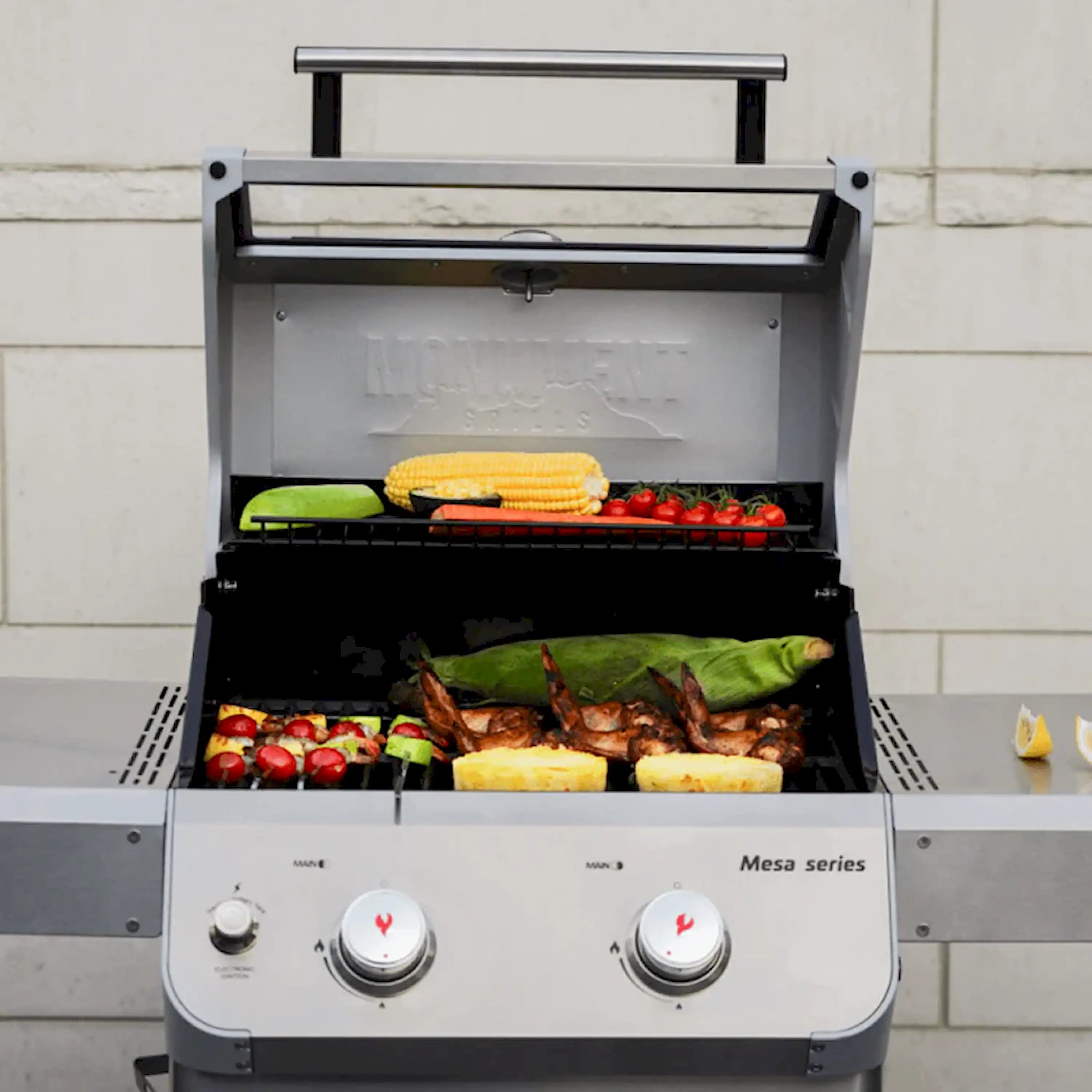 Propane grill open with cooking racks holding corn, meat, and vegetables