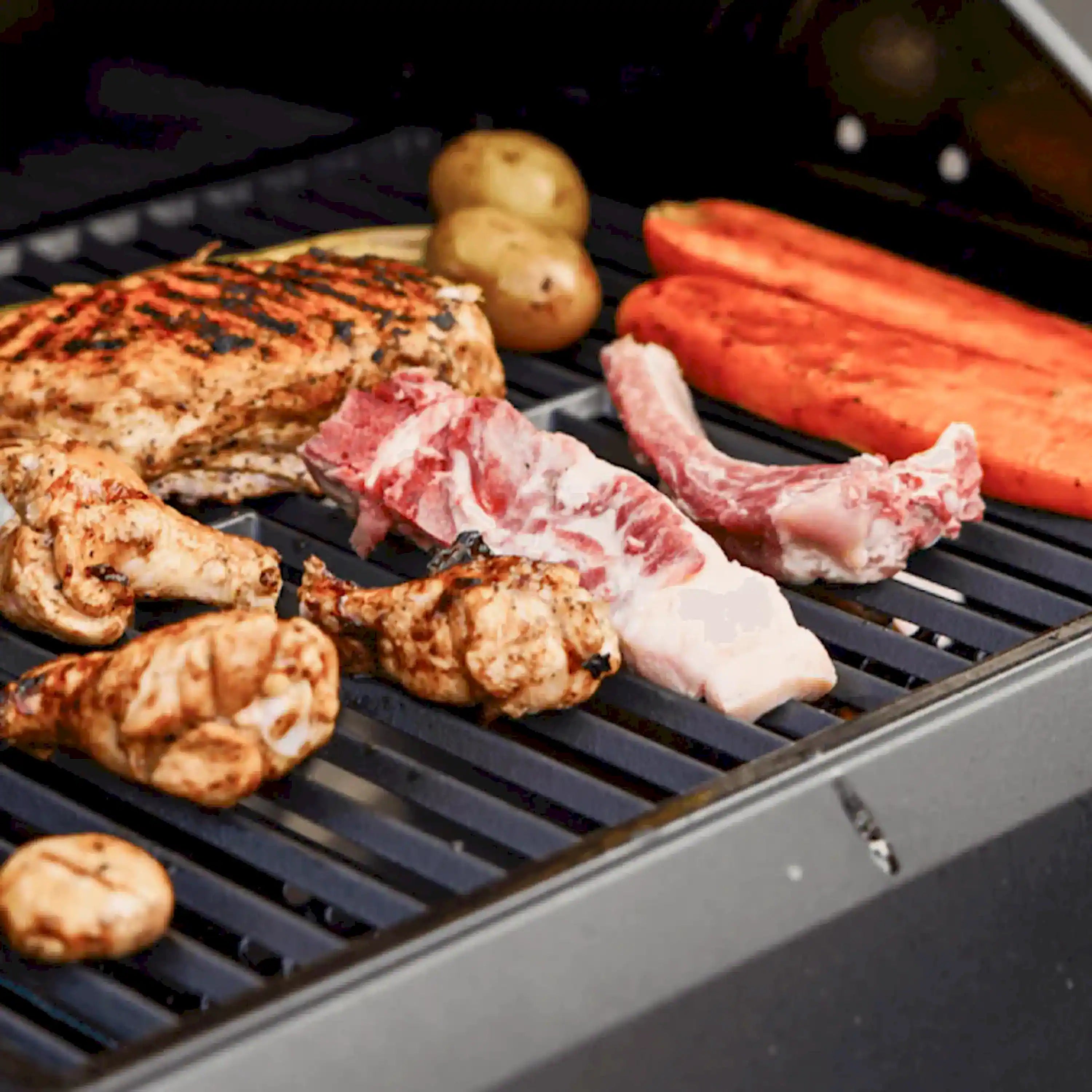 Two-burner propane gas grill with assorted meats and potatoes on black grates
