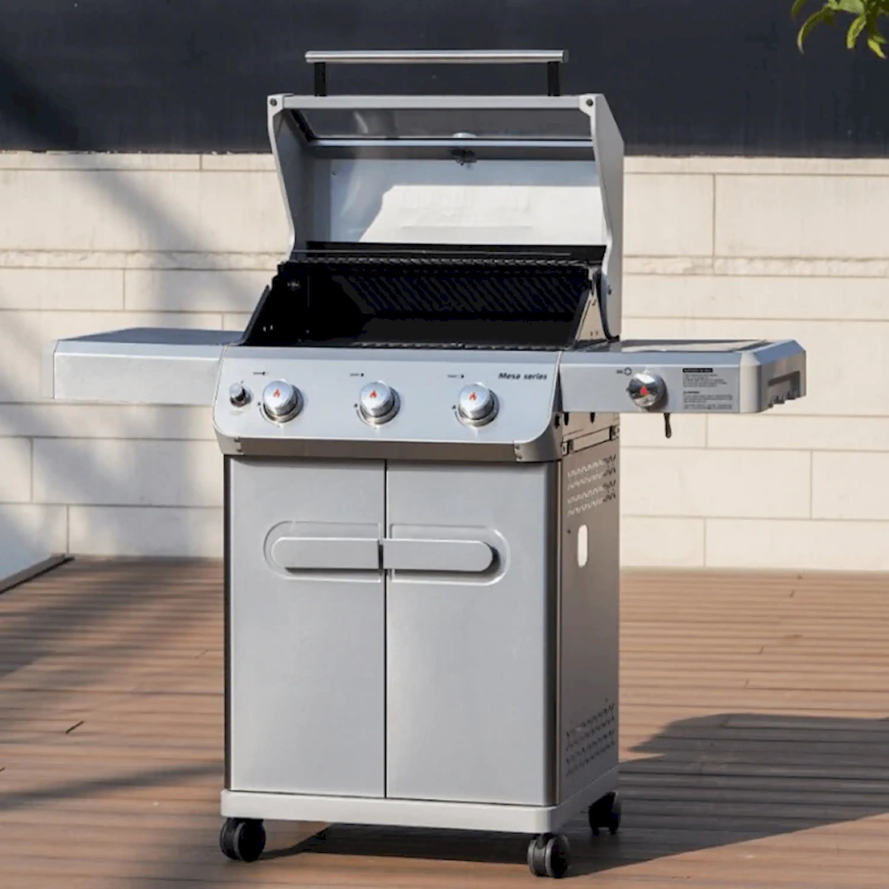 Stainless steel propane grill with three front control knobs and side shelf