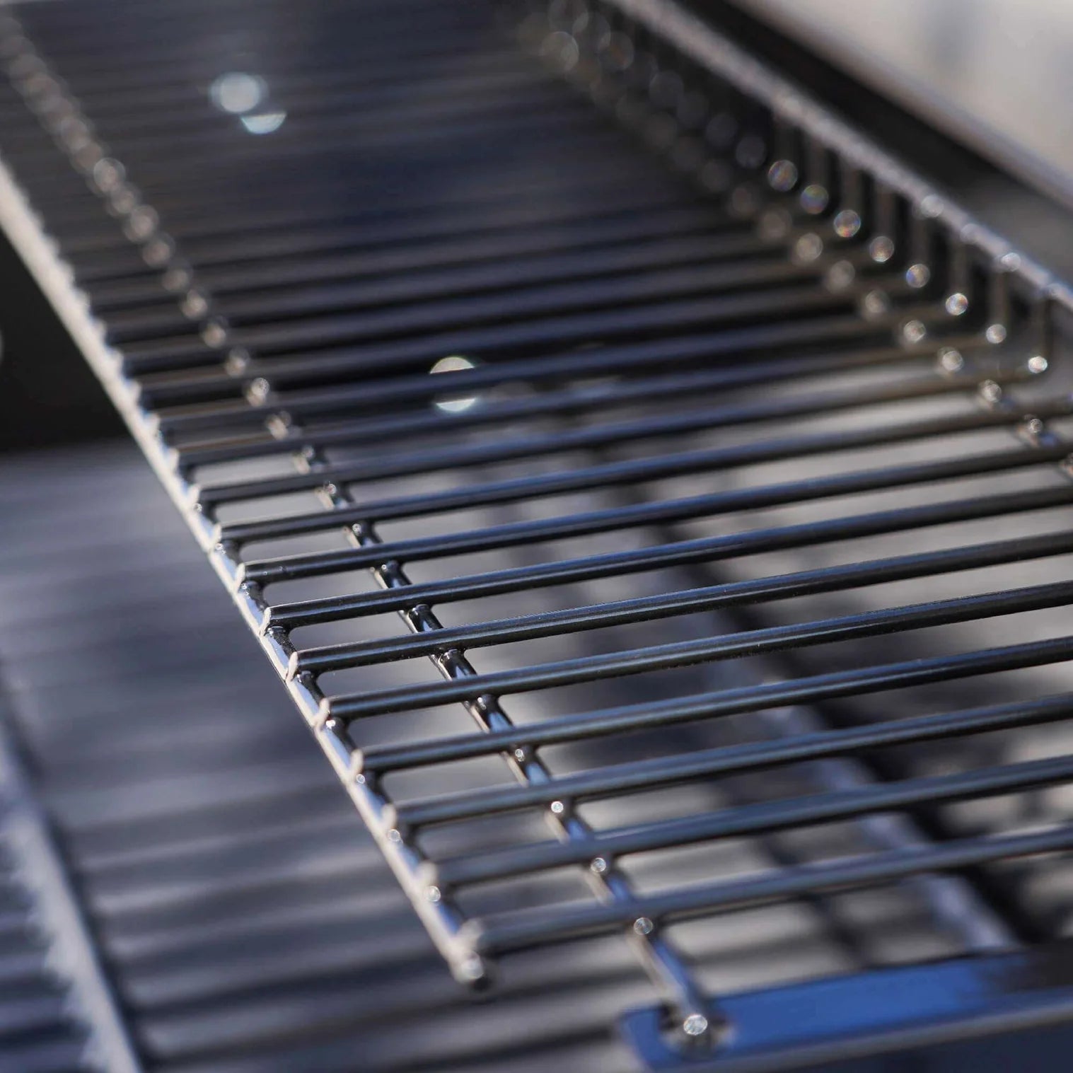 Close-up of dark grill grates and stainless steel frame inside the cooking area