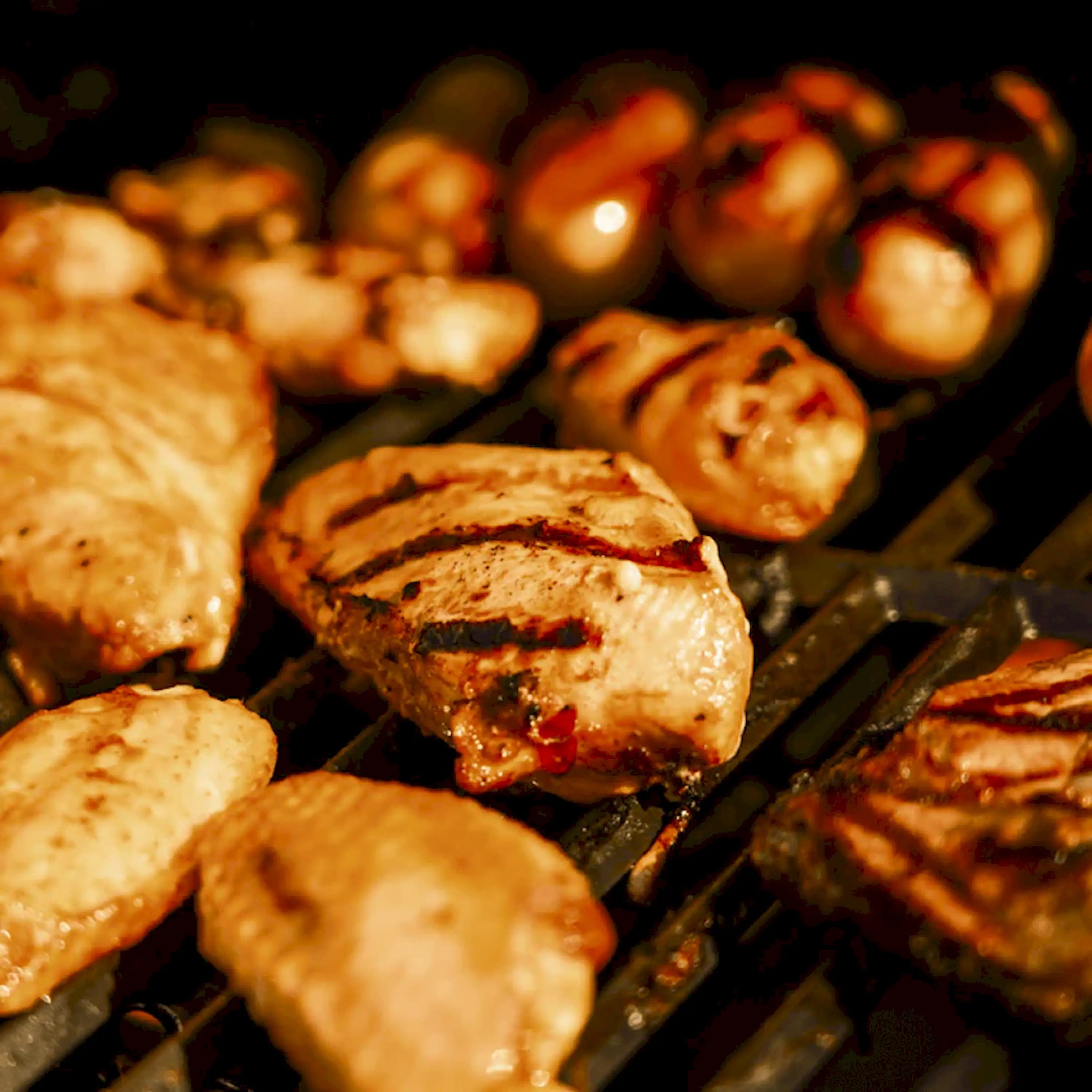 Grilled chicken on the cooking grates inside a gas grill