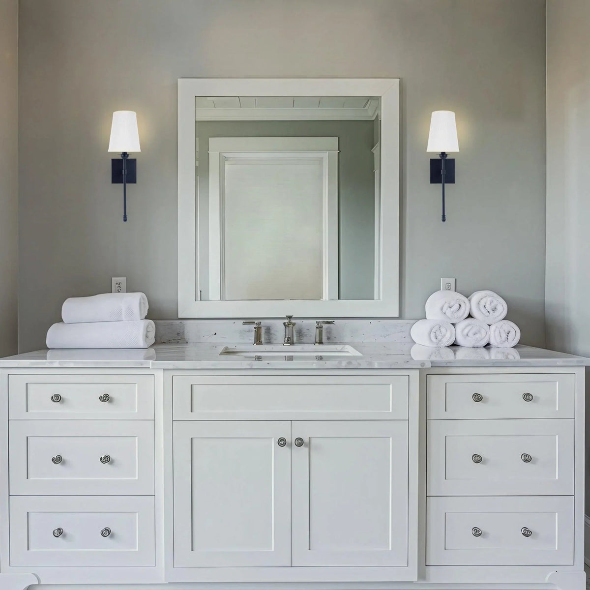 Black 1-light wall sconce with white fabric drum shade on bathroom wall