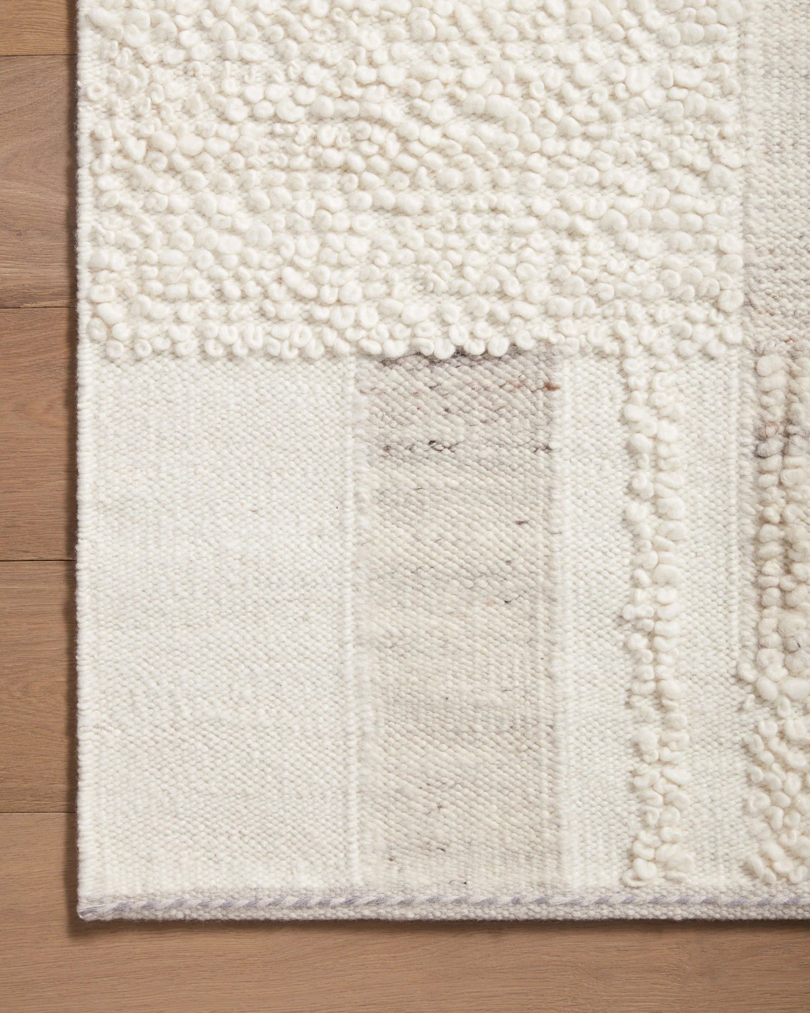 Ivory and pebble rug corner with tufted texture and subtle geometric weave