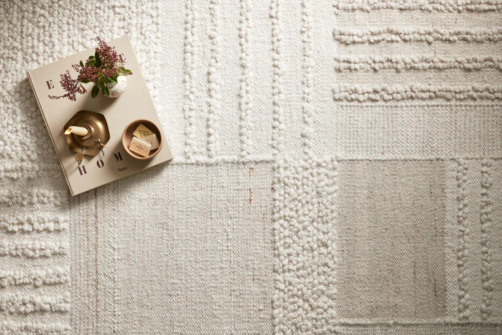 Ivory area rug close-up with stitched geometric blocks and raised loop texture