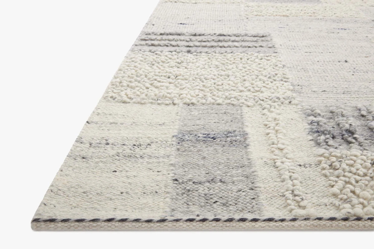Area rug with cream loop pile and gray slate block pattern, textured corner edge