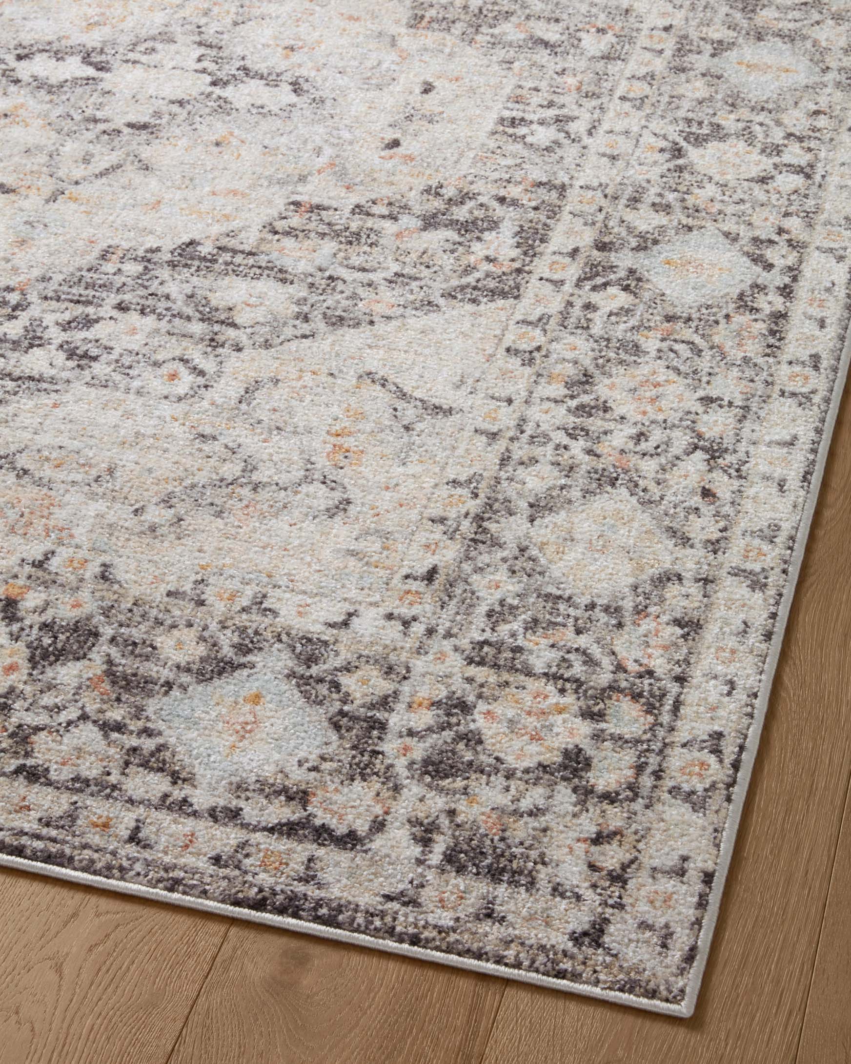 Charcoal and light gray distressed geometric area rug corner on wood floor