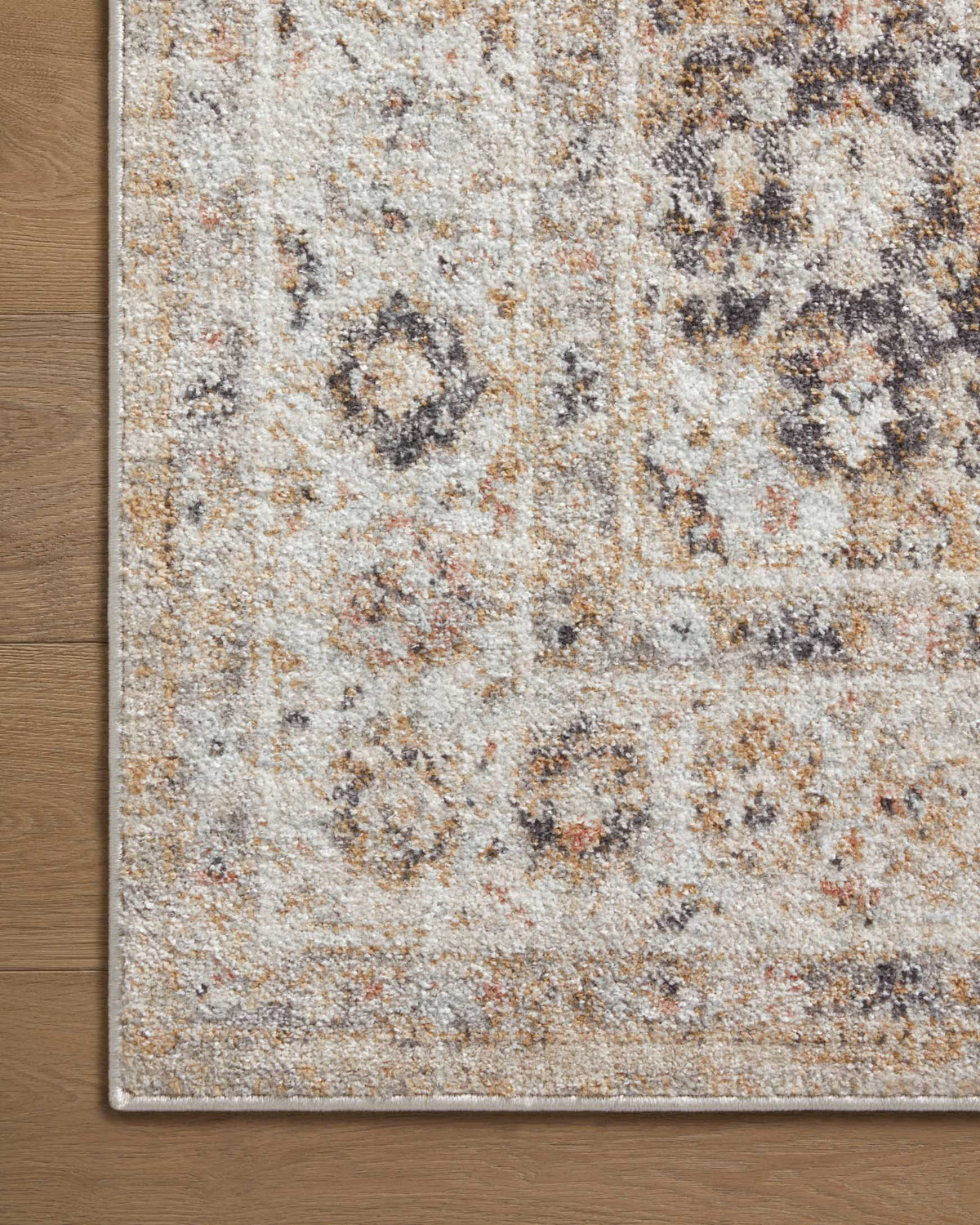 Beige distressed rug close-up with multicolor speckles and short border on edge