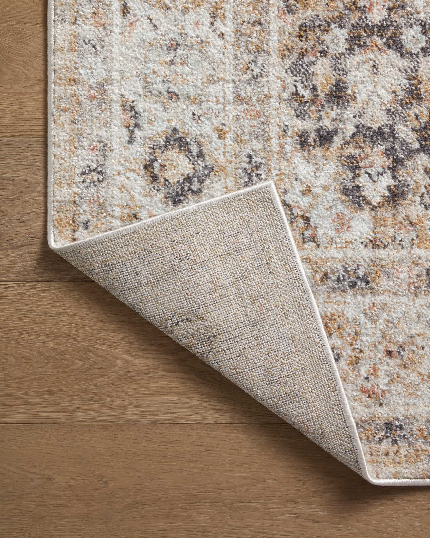 Beige area rug with distressed speckled texture and visible serged edge