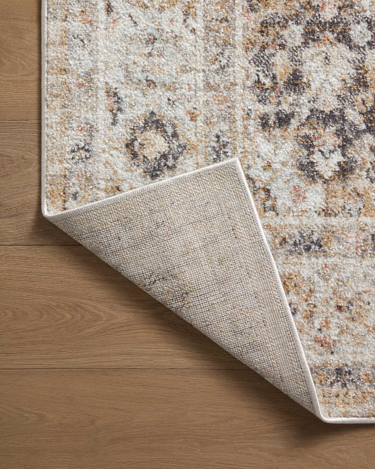 Beige runner rug corner rolled up to show textured weave and multicolor distressed pattern