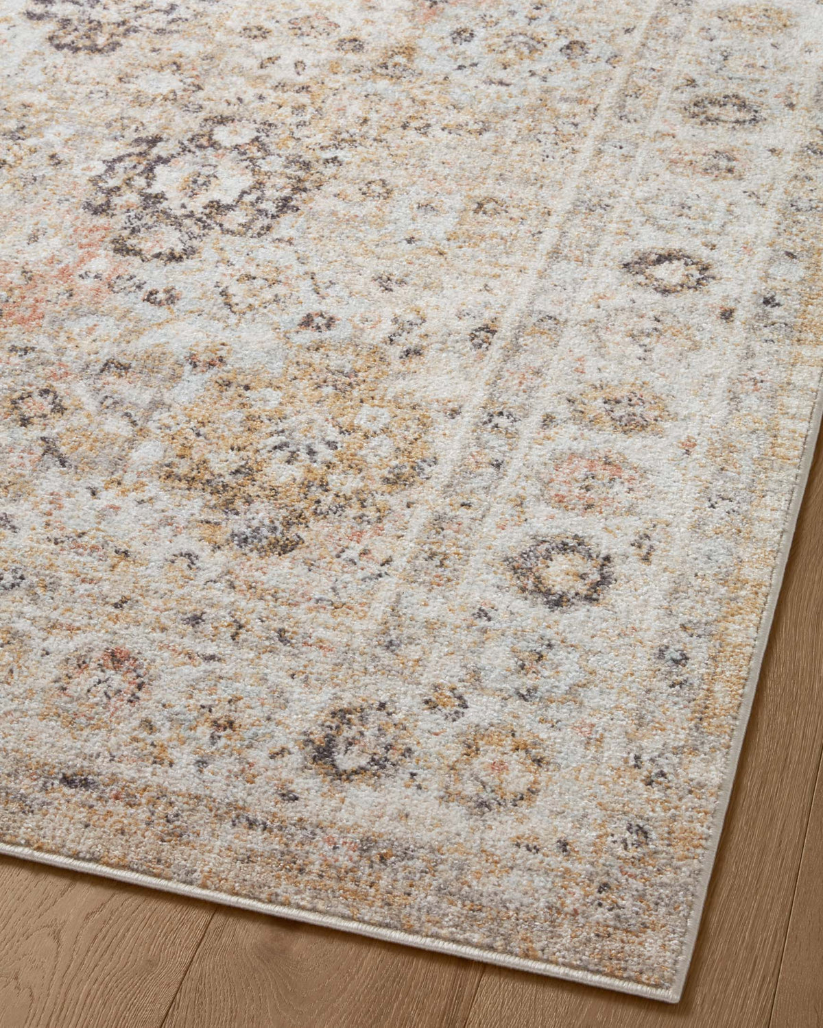 Beige area rug with repeating distressed motifs and subtle geometric lines