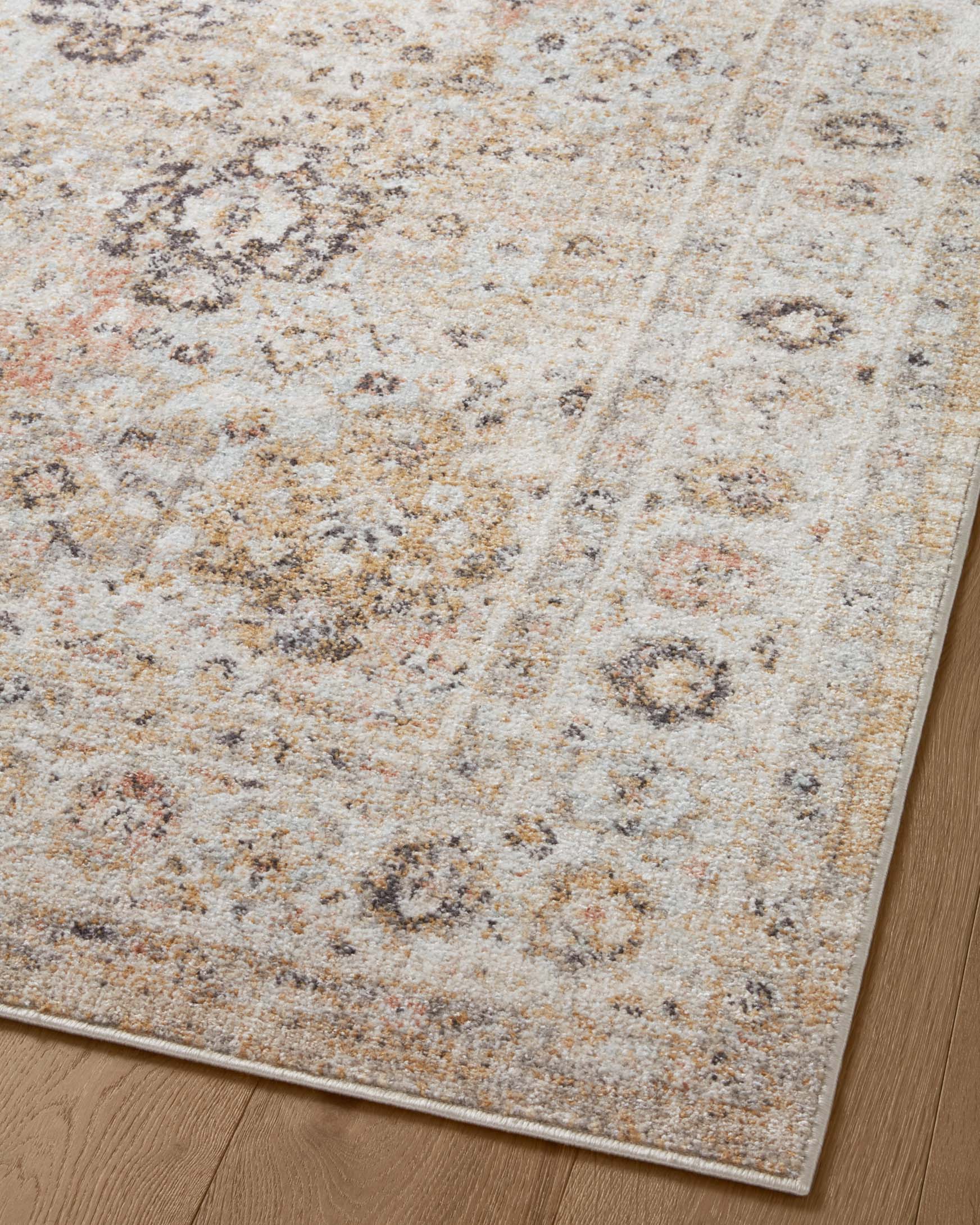 Beige area rug with distressed speckled medallion pattern, tonal light ground