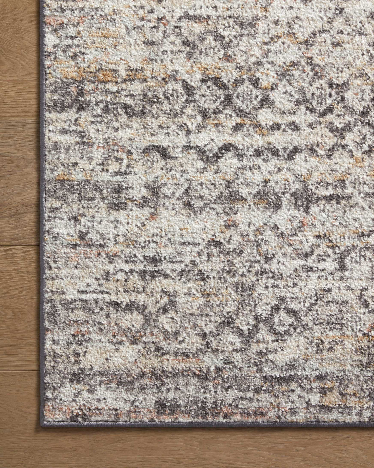 Gray area rug close-up with dense abstract fleck pattern and thin dark trim