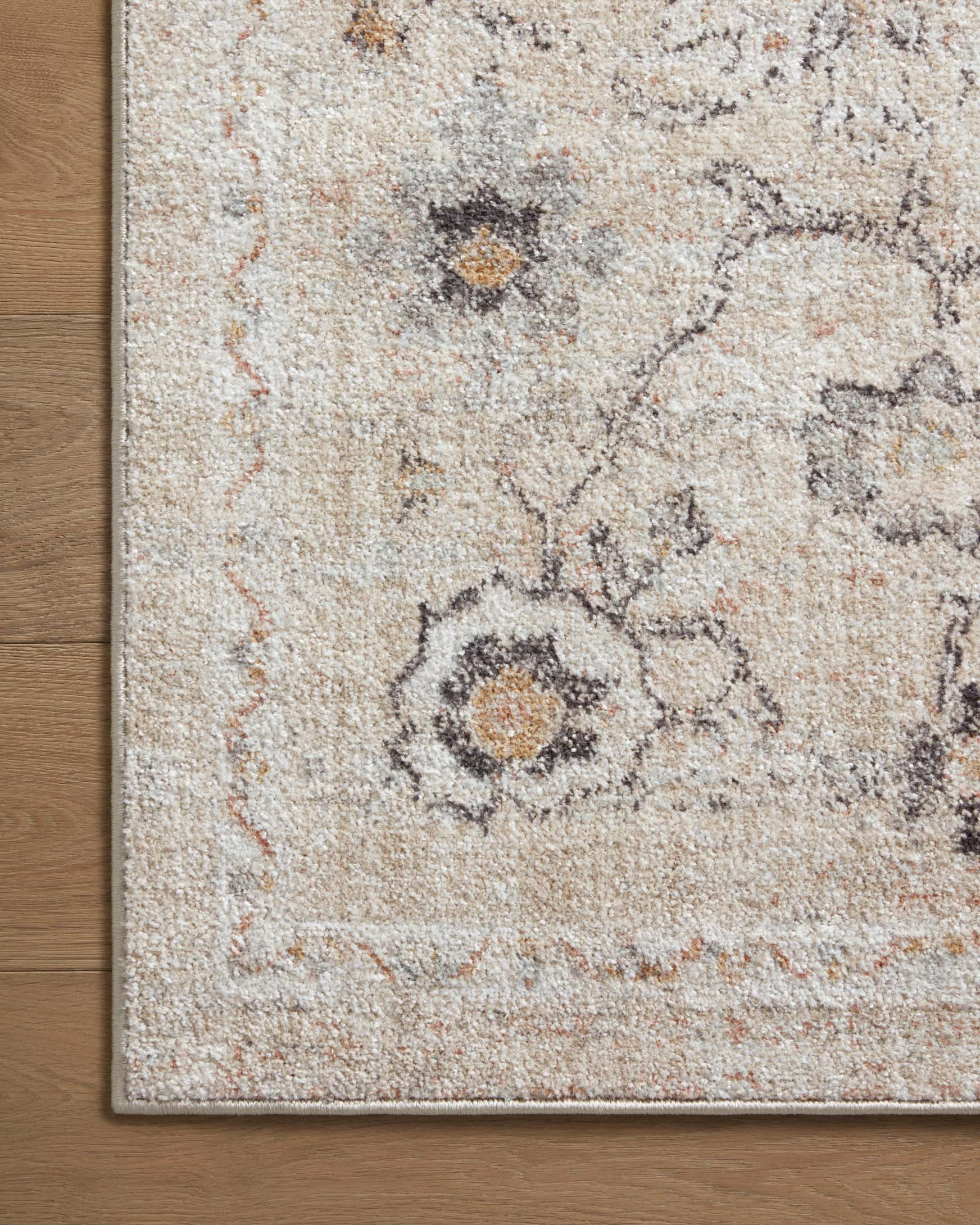 Accent rug close-up with faded floral medallion motifs in beige, gray, and tan