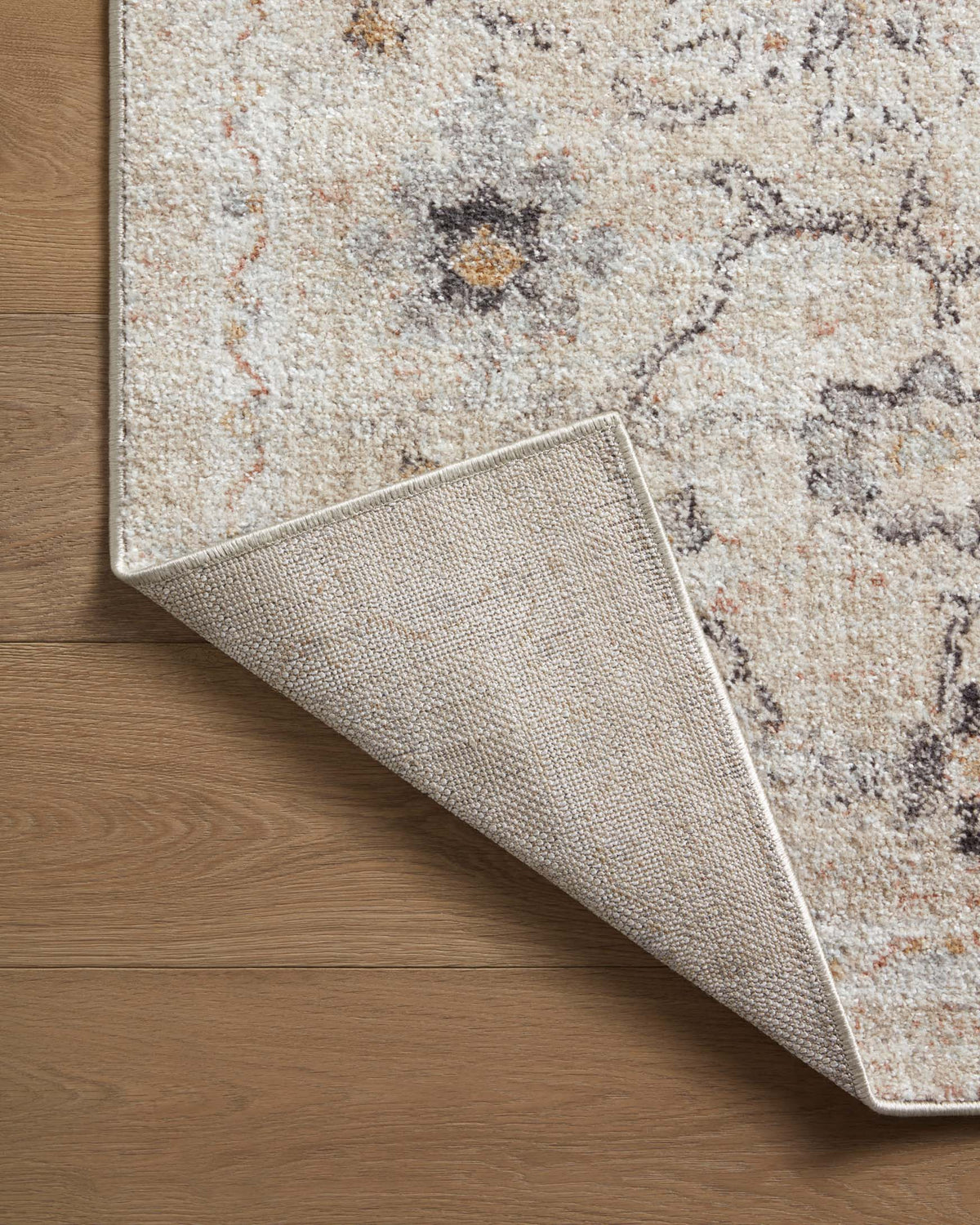 Natural area rug edge with woven backing and distressed motif, gray and tan tones