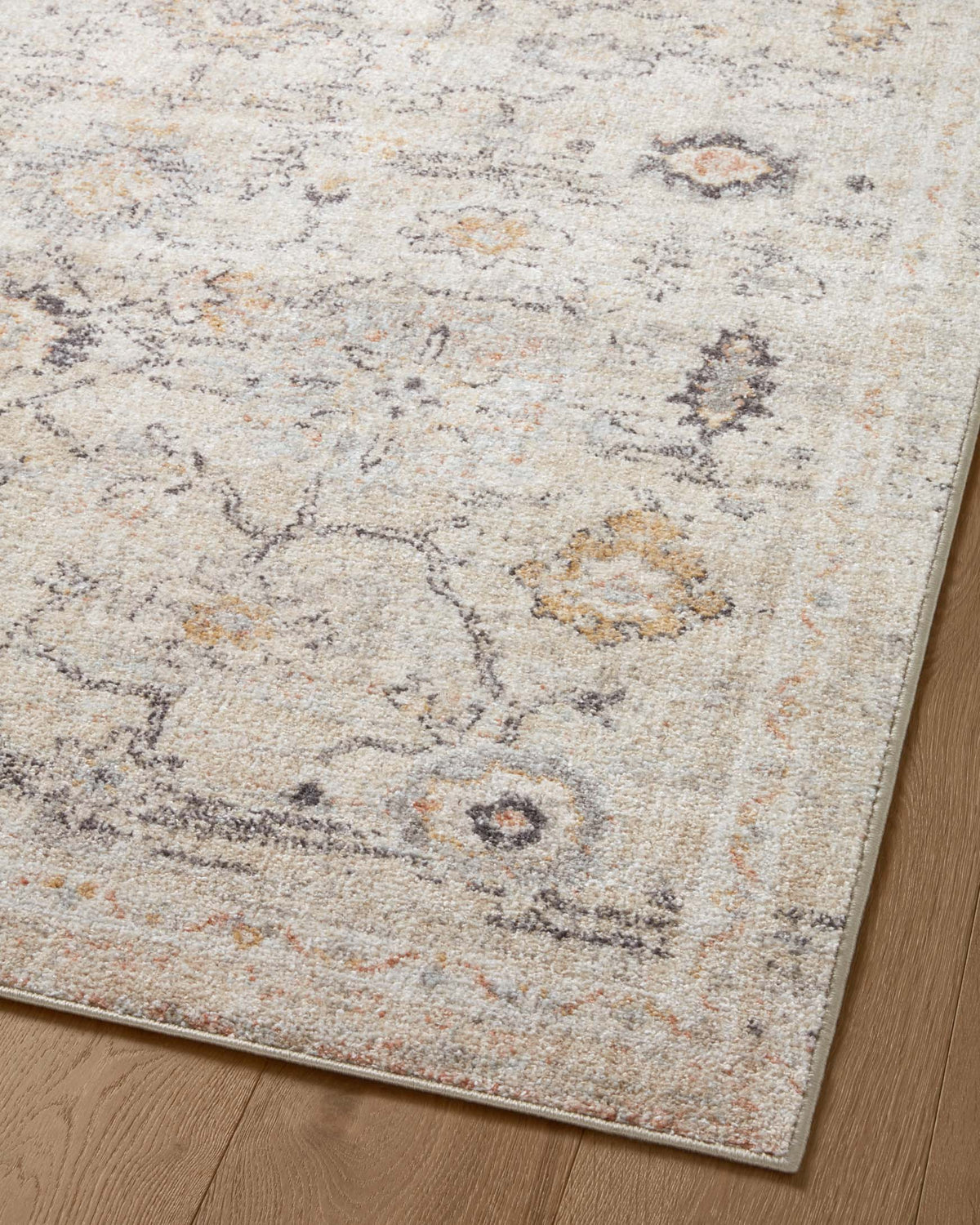 Natural accent rug close-up with scattered medallion motifs in cream, gray, and tan
