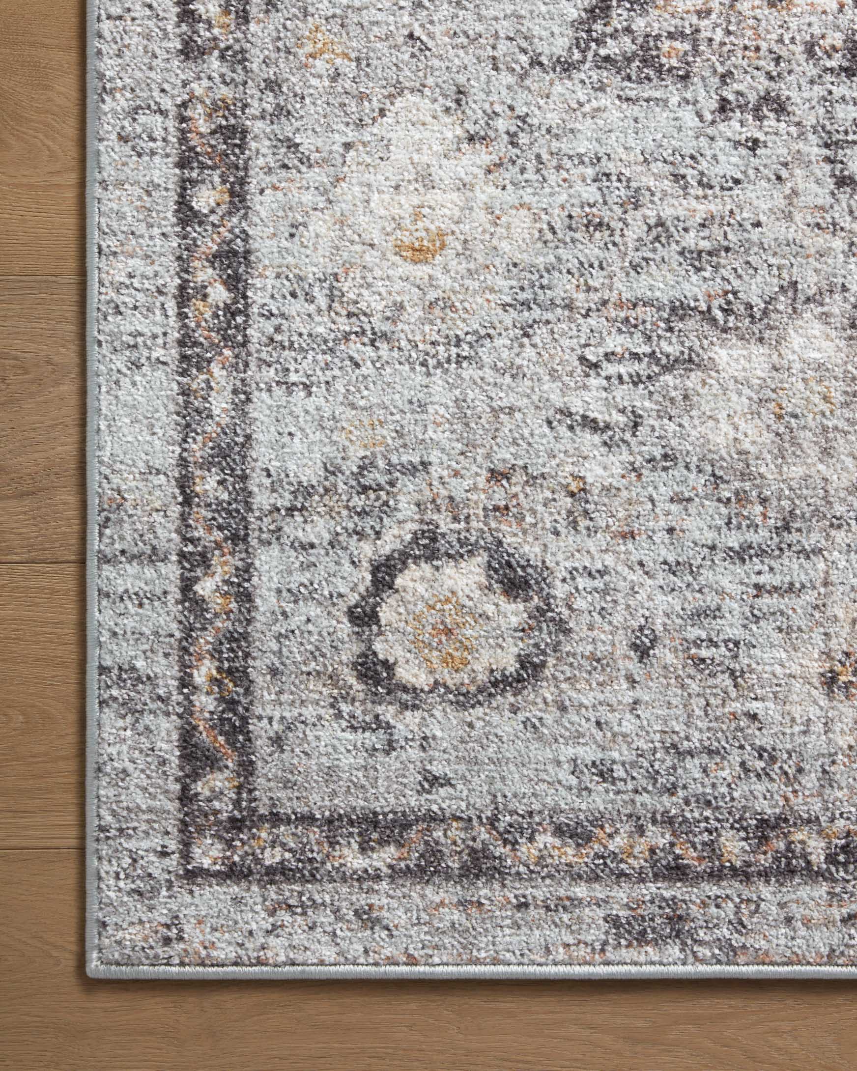Close-up of sky and gold area rug corner with distressed medallion motif and border