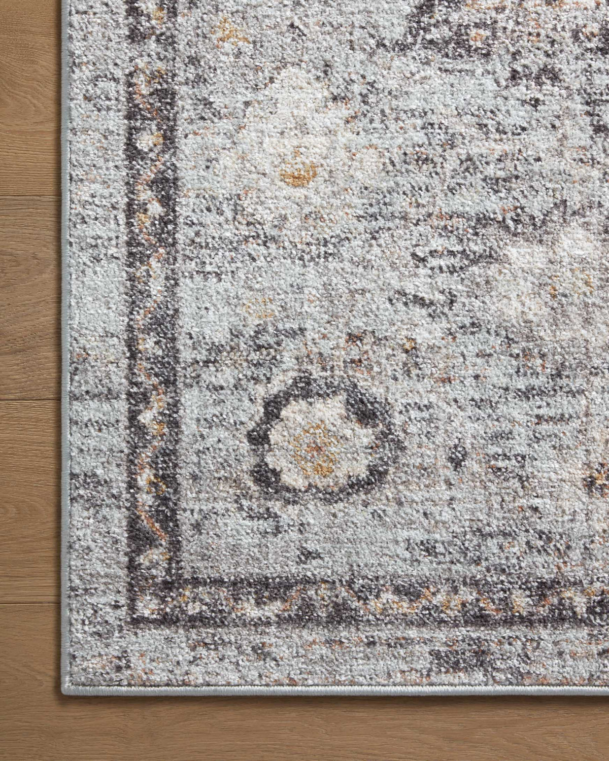 Gray runner rug corner detail with distressed motifs and gold flecks