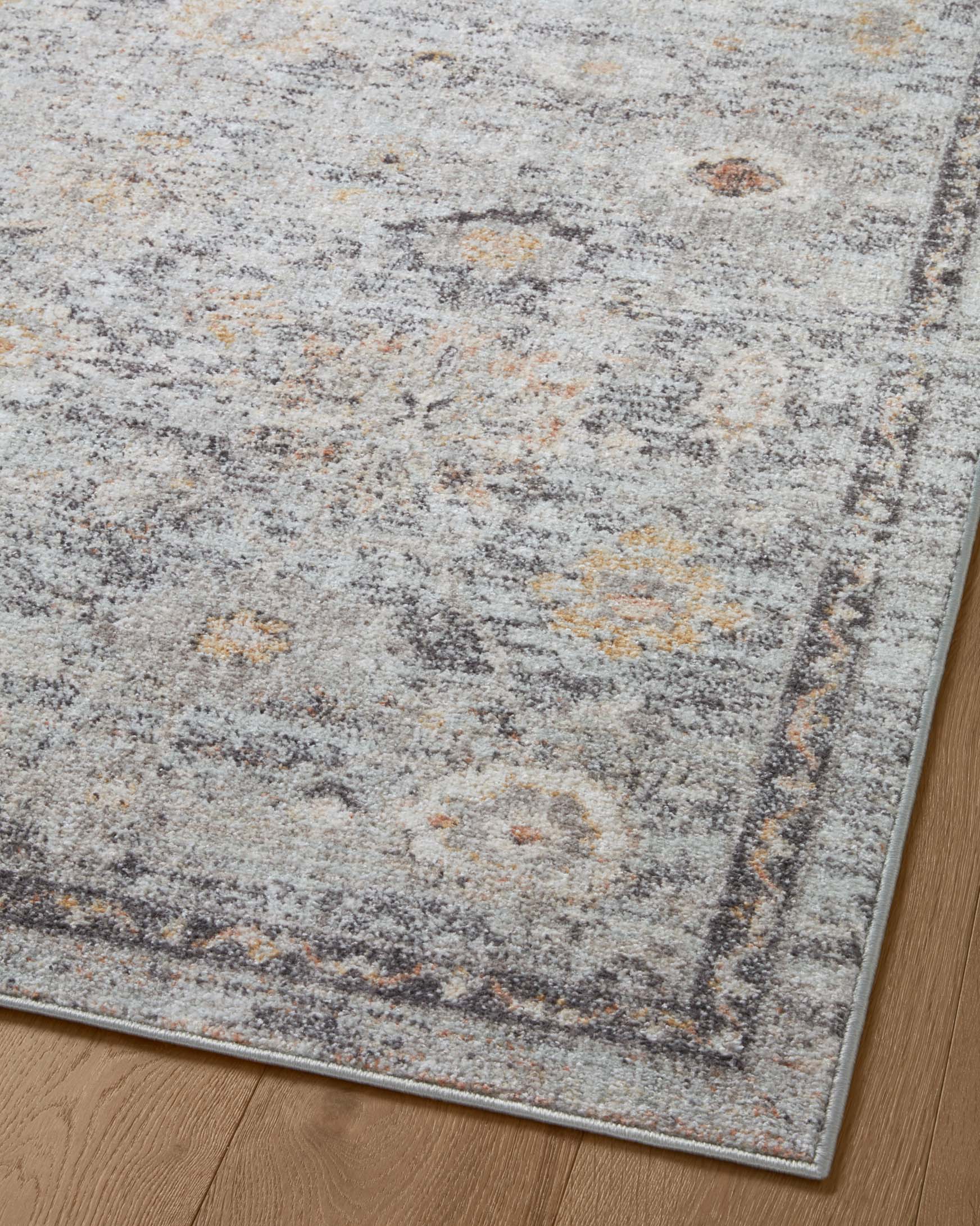 Close-up of distressed abstract area rug in light gray with muted sky blue and gold flecks