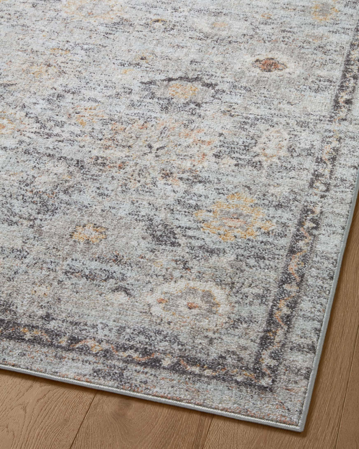Accent rug close-up with mottled gray texture, scattered gold specks, and dark border