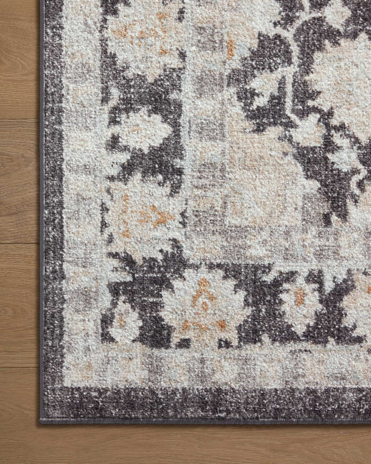 Charcoal and natural abstract area rug close-up with distressed motifs and border, low pile.