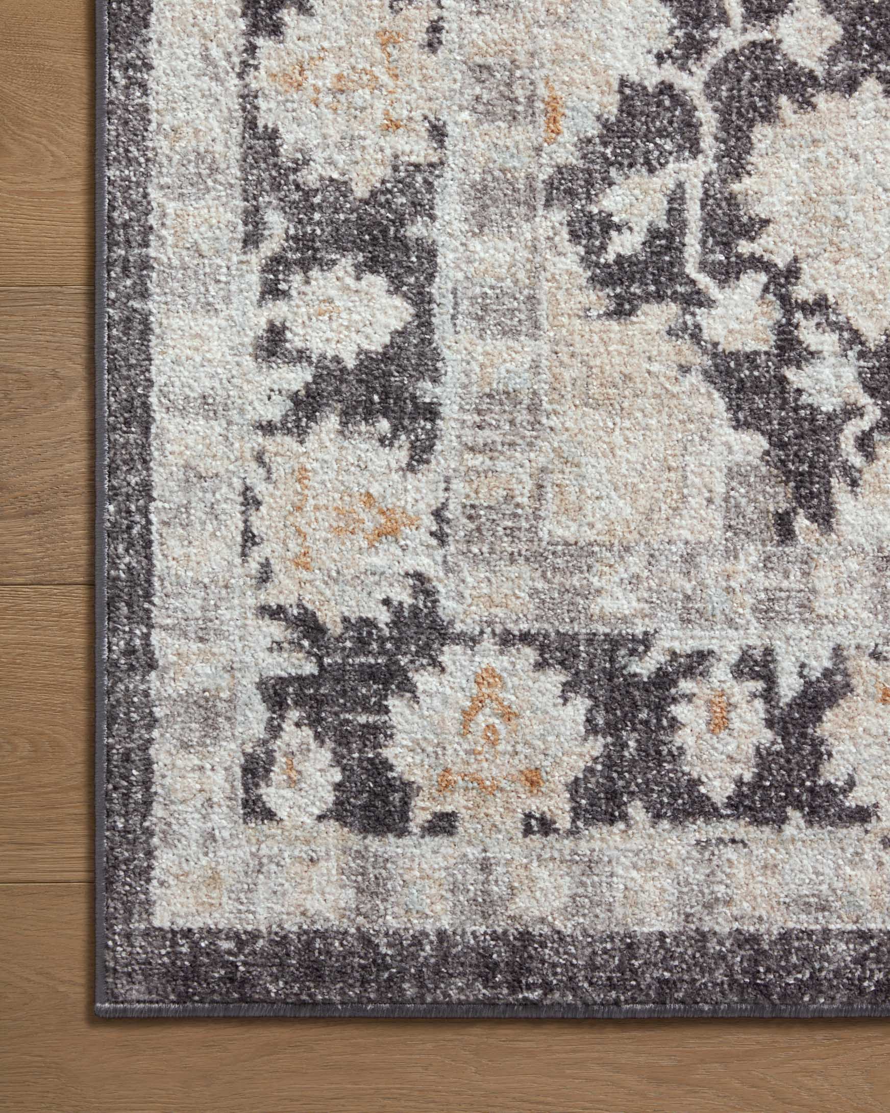 Charcoal and natural area rug close-up with distressed pattern and dark edge trim.