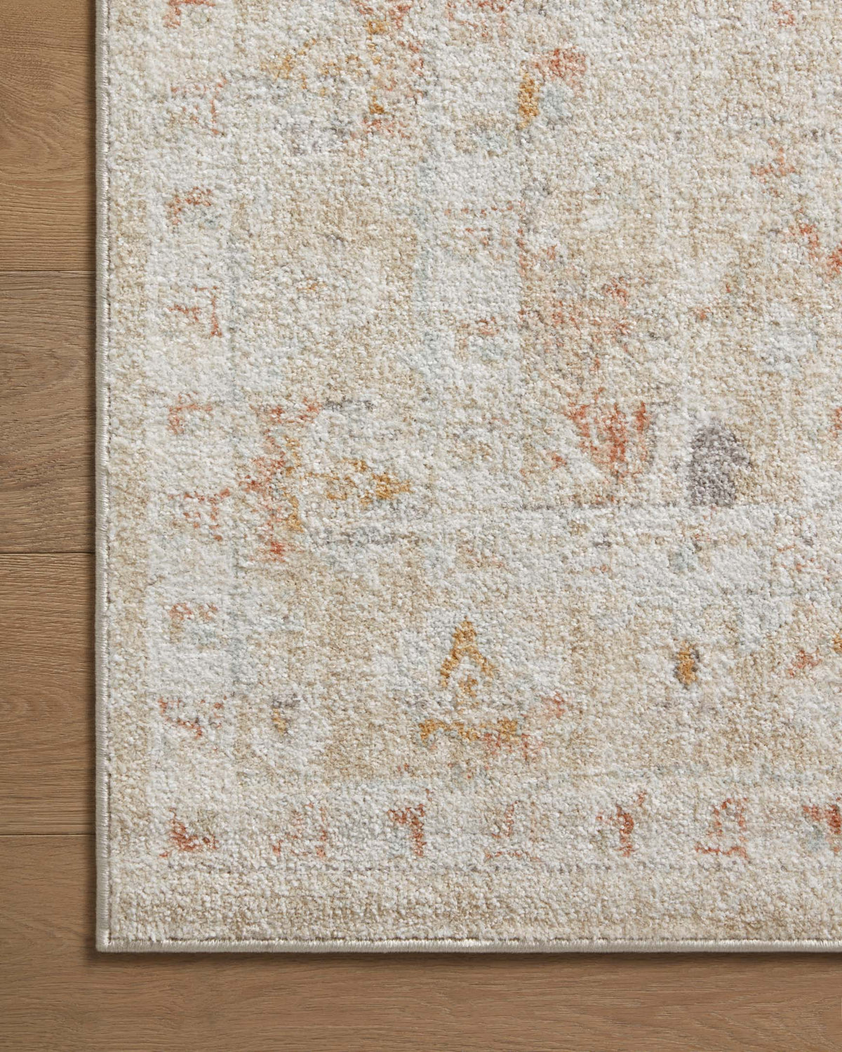Sand rug close-up with distressed mottled texture and rust-orange specks along the edge