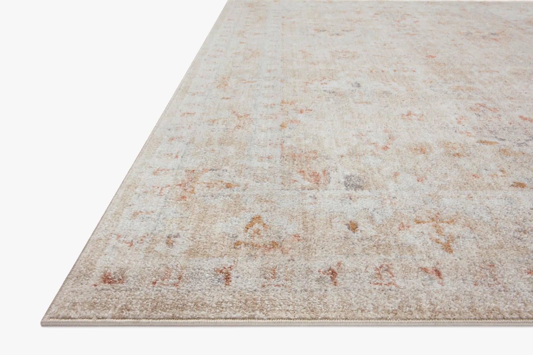 Accent rug in light beige with distressed rust and orange speckles, corner angled view