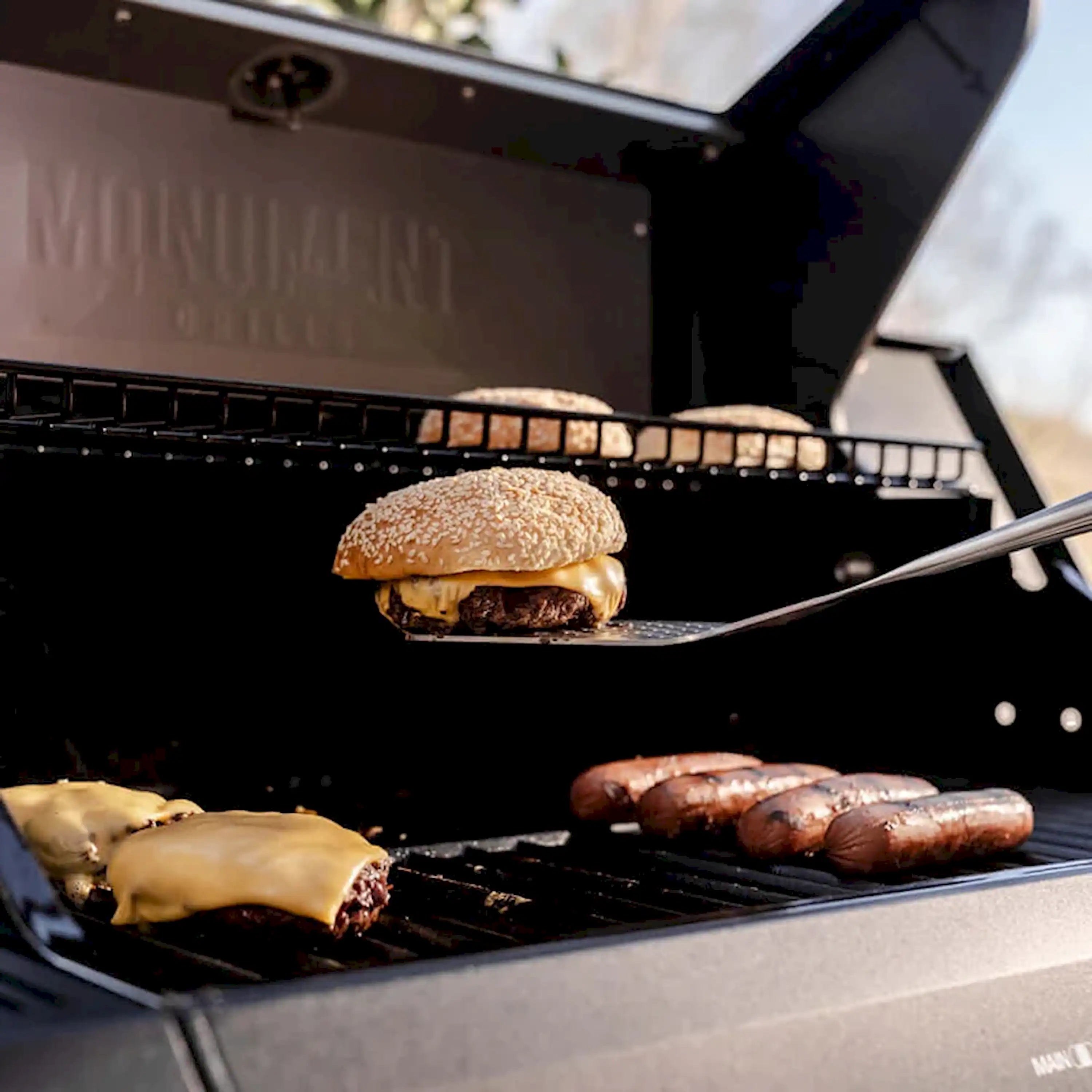 Open grill with burgers and sausages on cooking grates