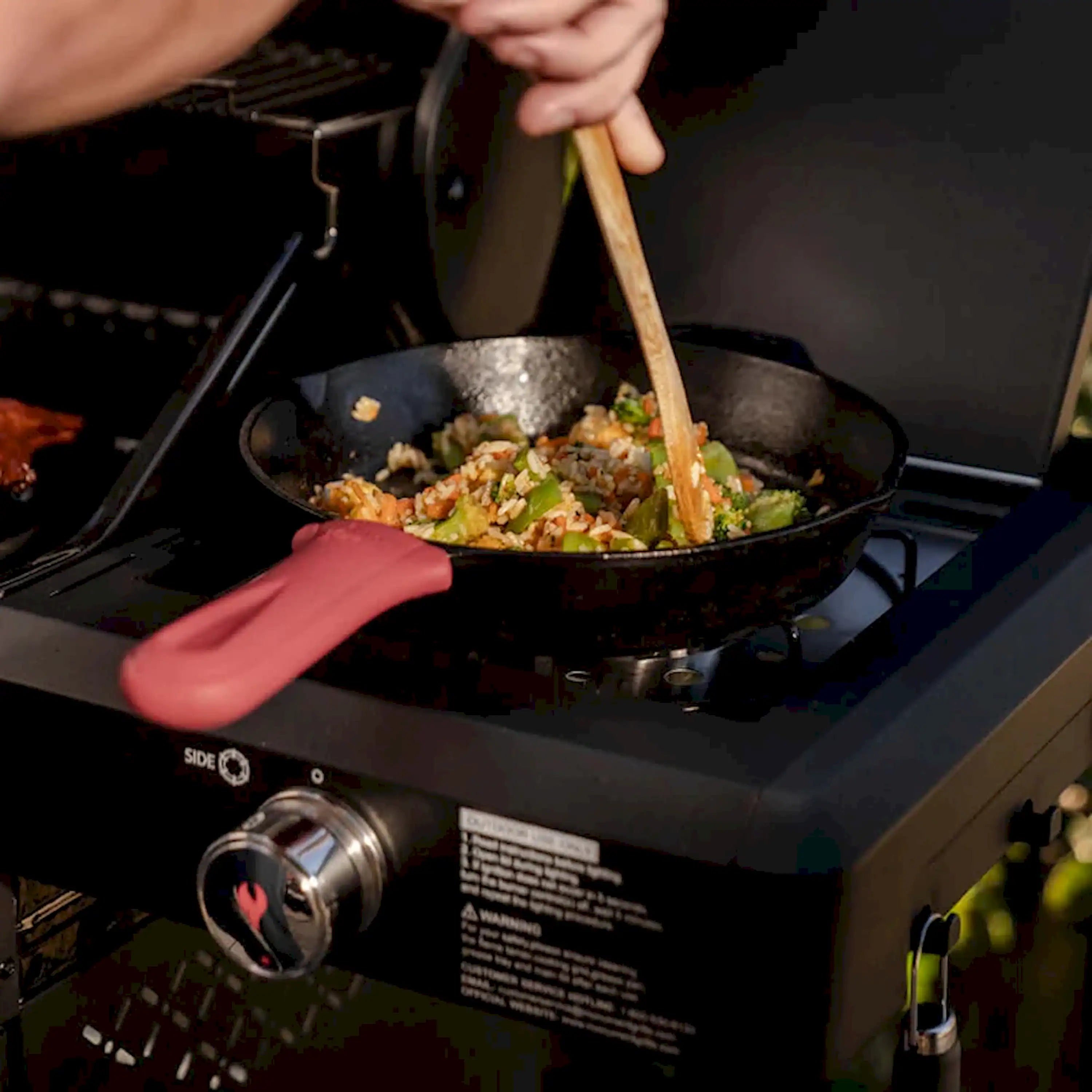 Open 3-burner propane grill with pan cooking vegetables