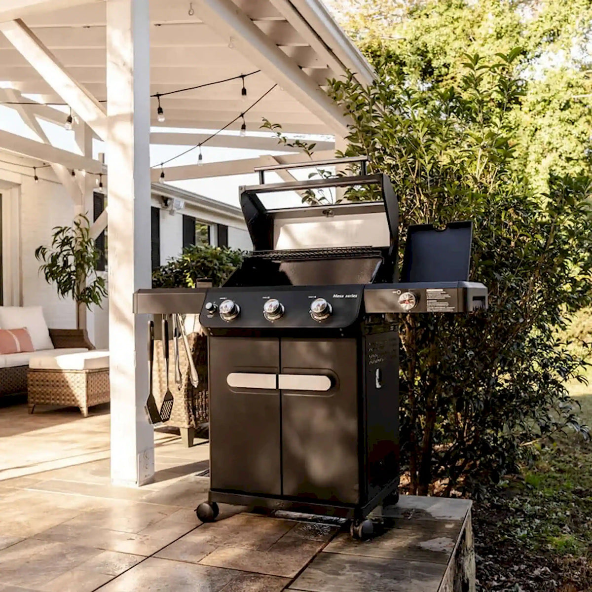 Black propane grill on patio with lid open and side controls visible