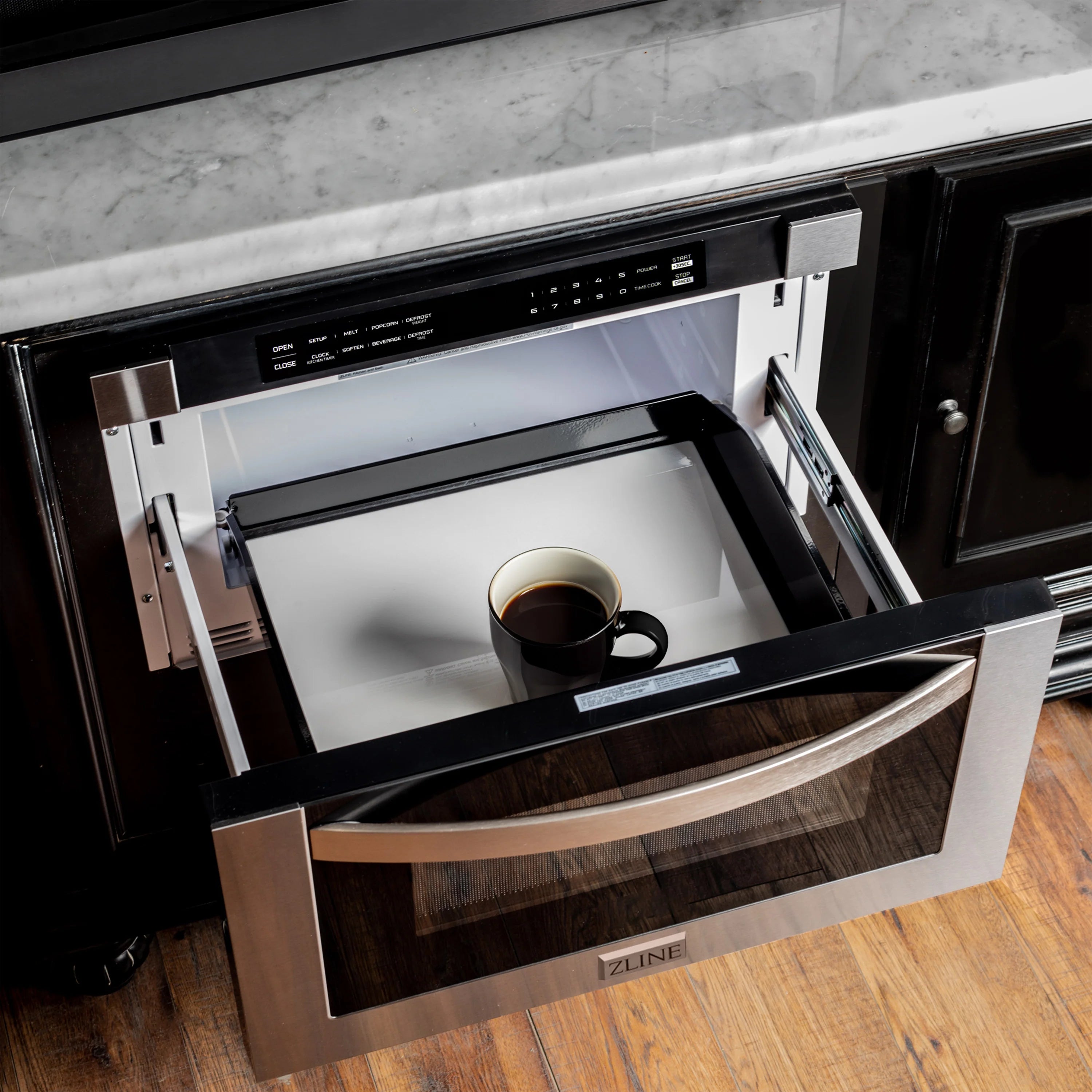 Stainless steel microwave drawer pulled open, showing interior cavity with cup