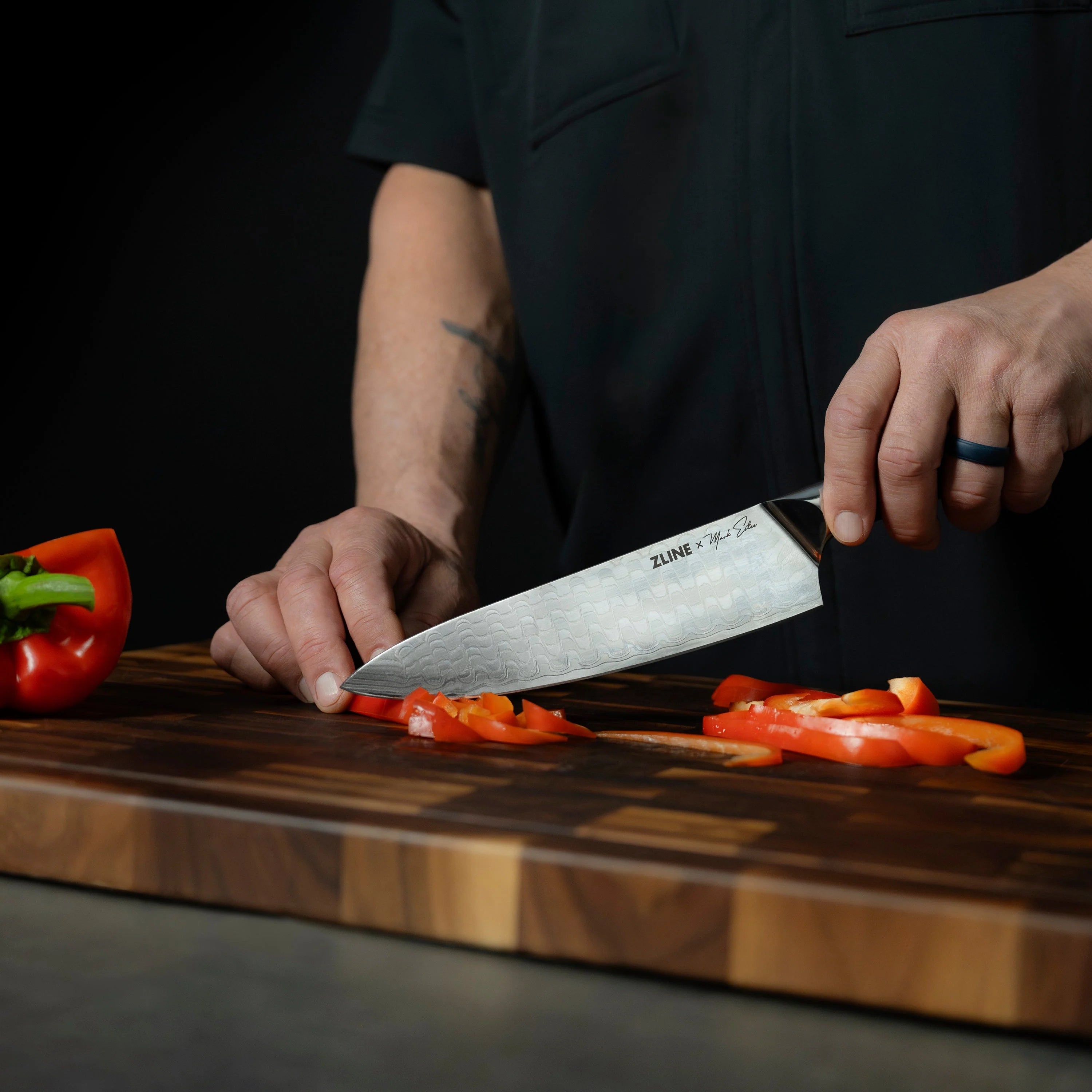 Japanese Damascus chef knife slicing orange vegetables on a wooden cutting board