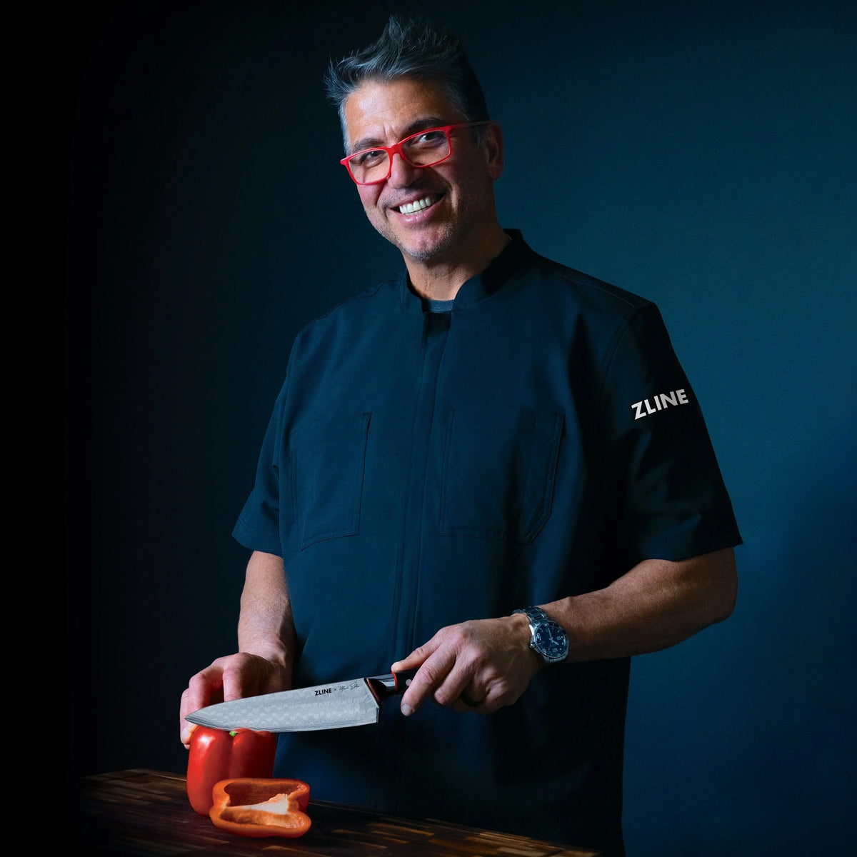 Professional chef holding Japanese Damascus chef knife near sliced peppers