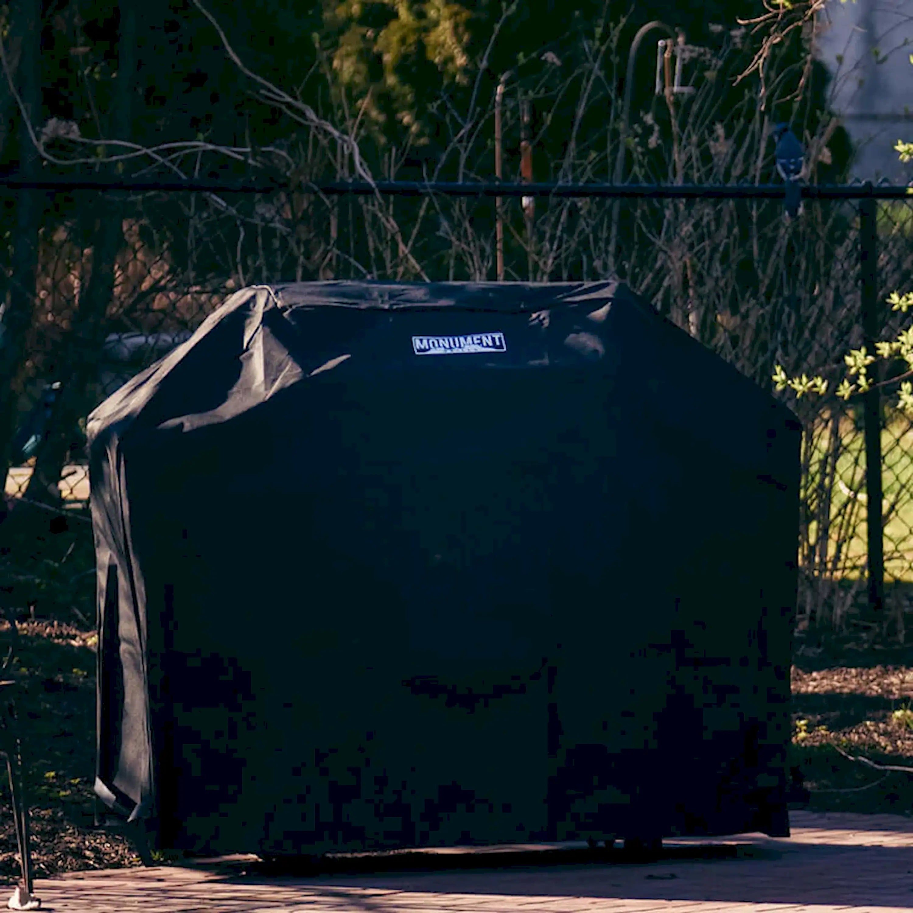 Black 4-burner gas grill cover stretched over grill outdoors
