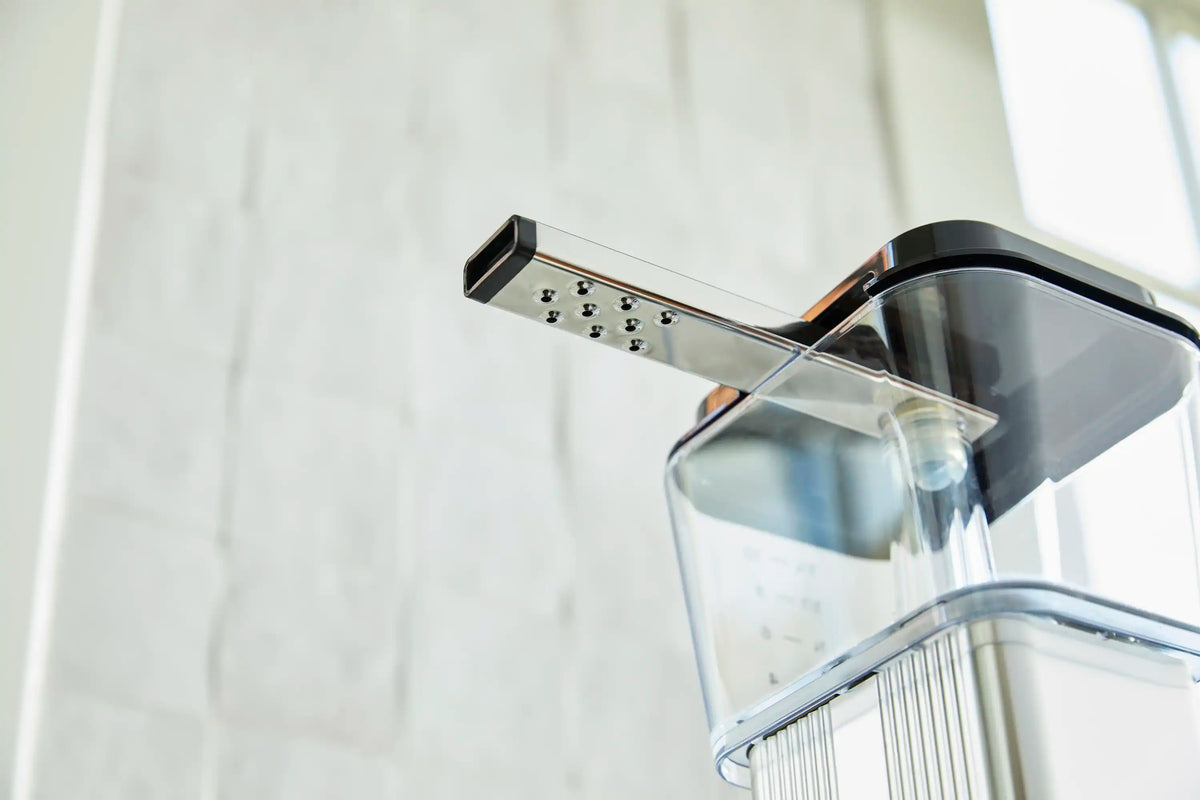 Moccamaster brew spout releasing into clear carafe above the black coffee maker base.