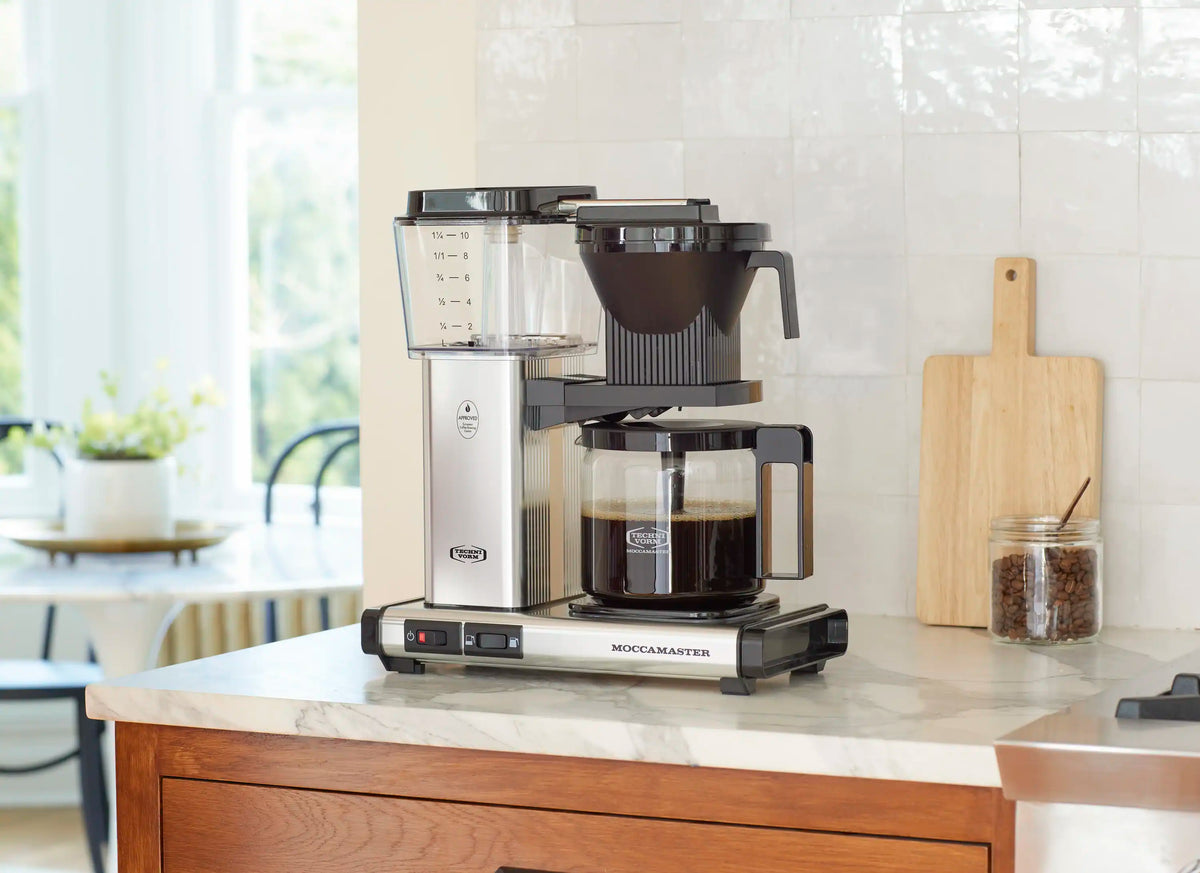Moccamaster 10-cup coffee maker with glass carafe and black funnel on counter.