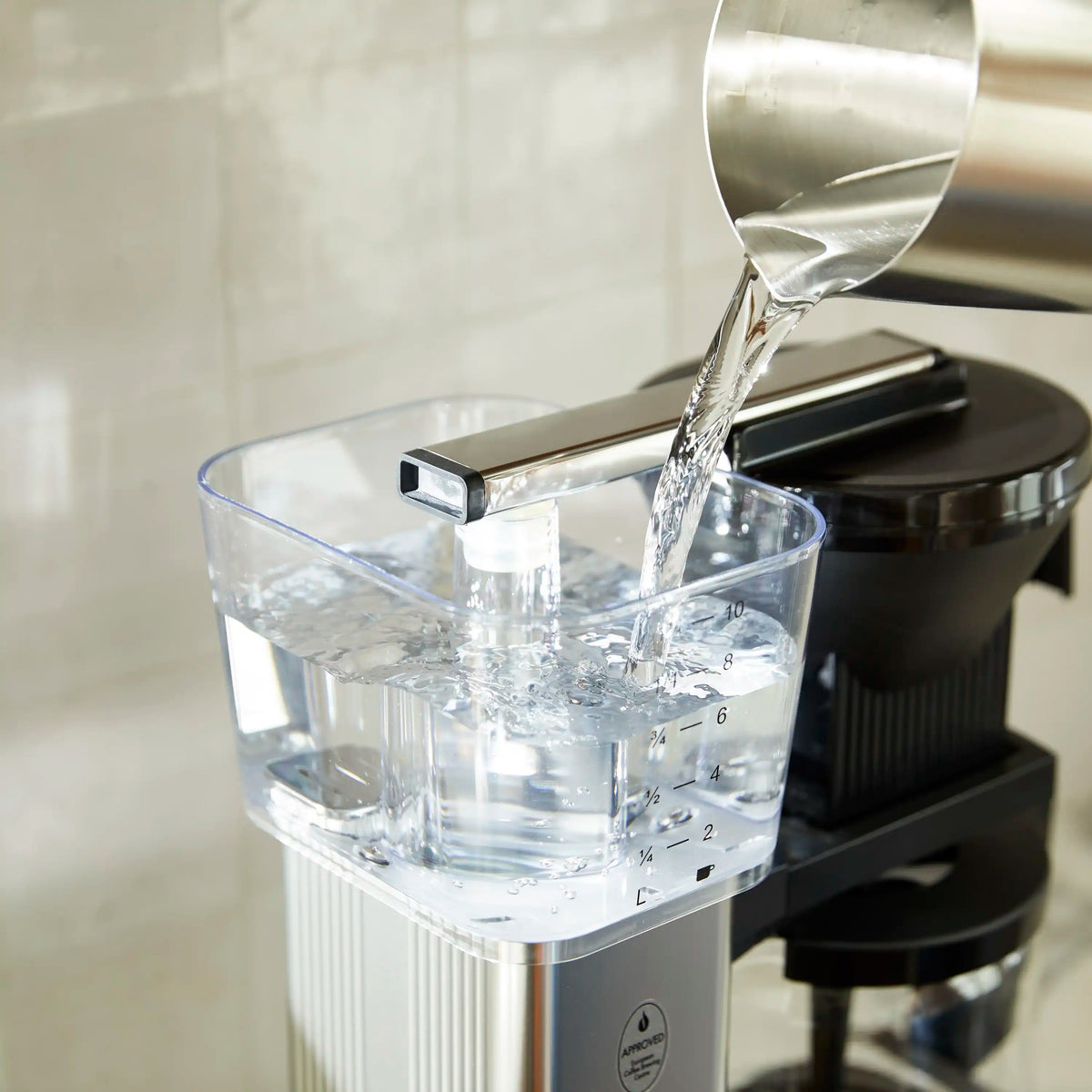 Moccamaster 10-cup glass carafe filling under spout on black coffee maker base