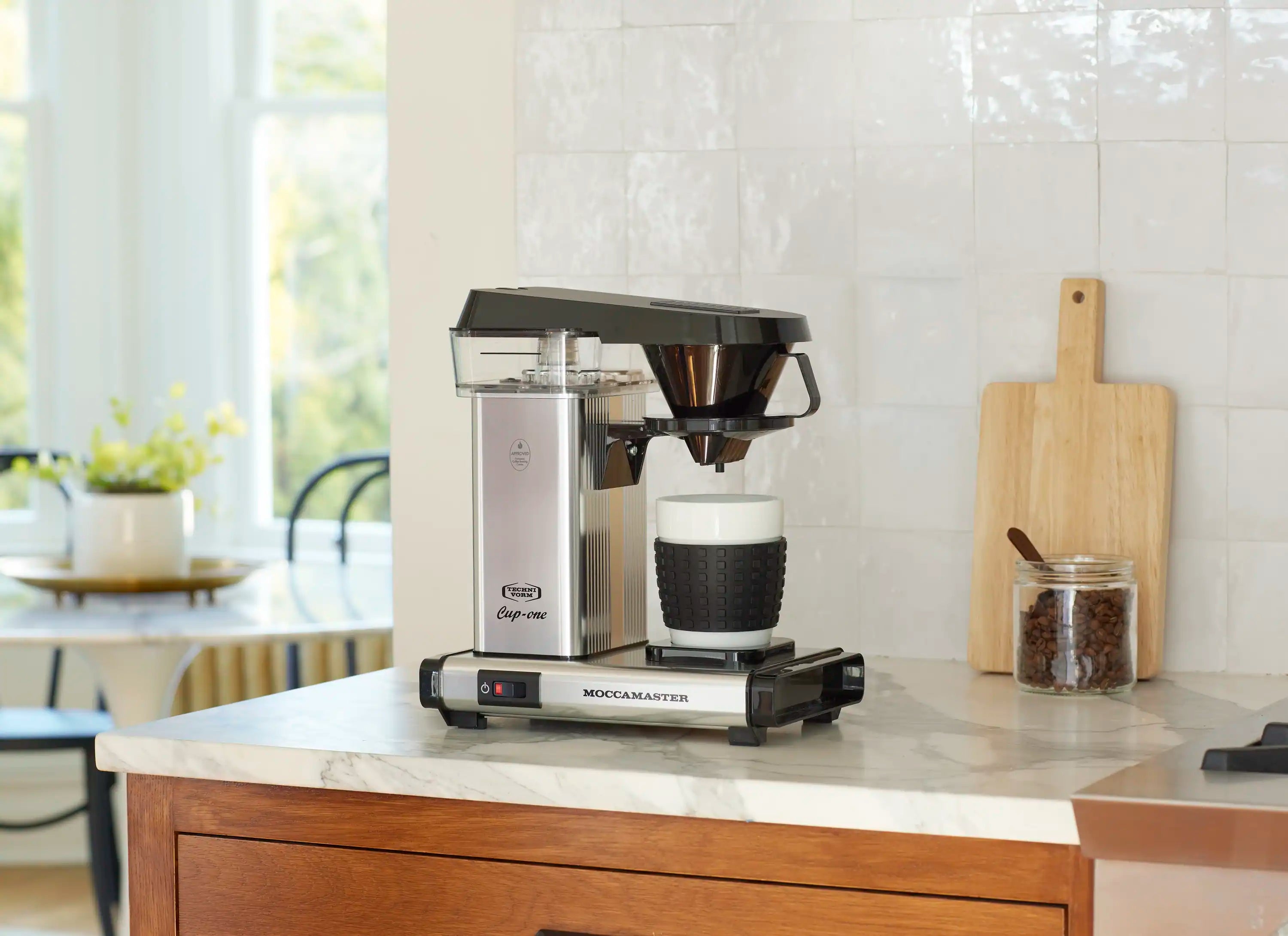 Single-cup coffee maker in polished silver with black funnel and drip tray