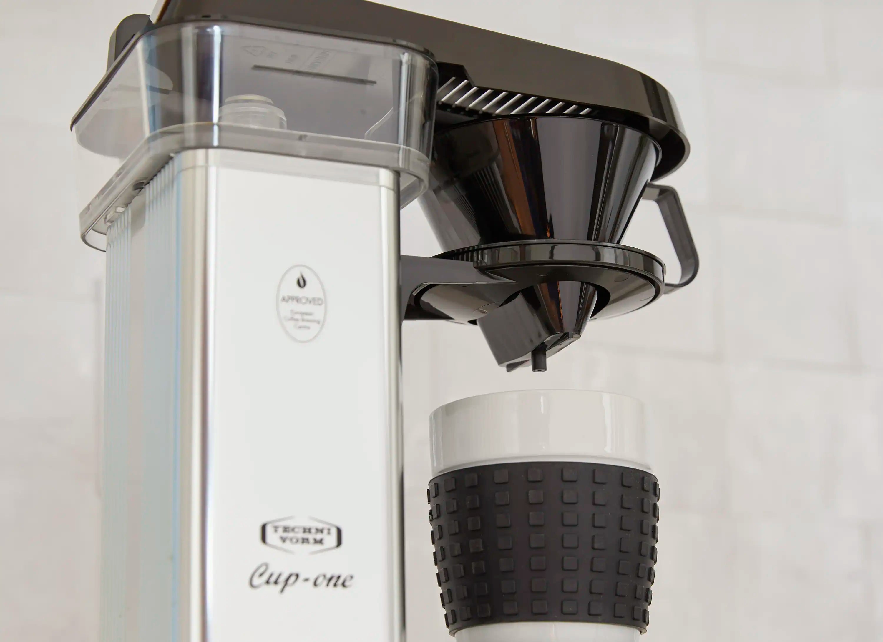 Single-cup coffee maker close-up: clear tank and black funnel with spout