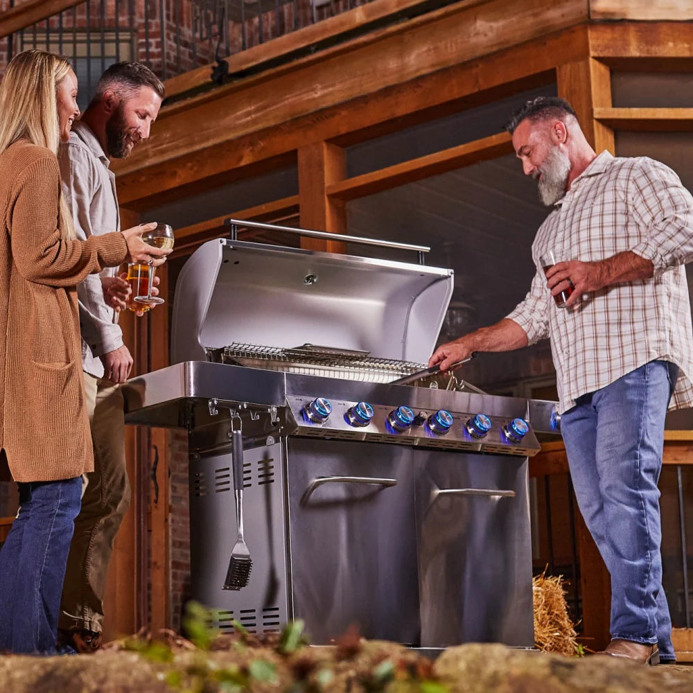 Stainless steel propane gas grill with lid open during cooking with multiple burners