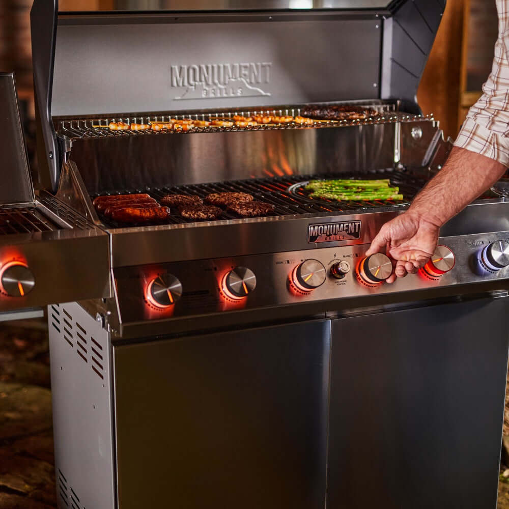 Stainless steel gas grill with open lid, lit burners, and front control knobs