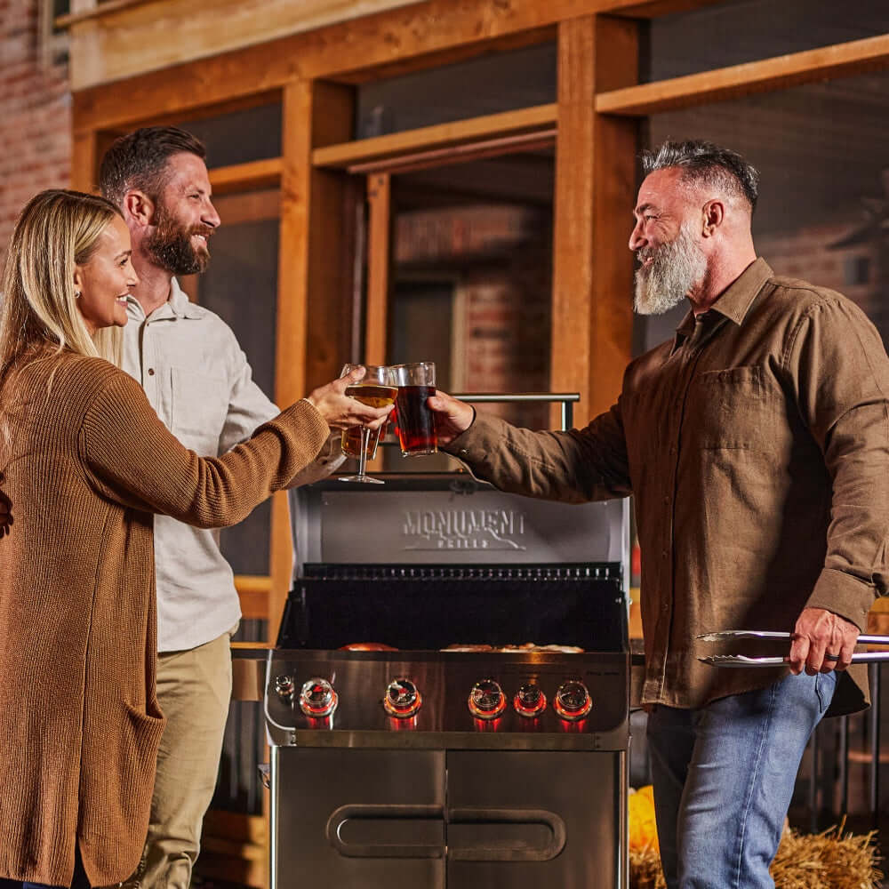Stainless steel 4-burner propane grill with people holding drinks outdoors