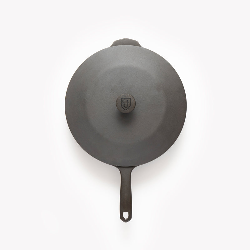 Round cast iron skillet lid with central knob, dark gray, loop handle underneath