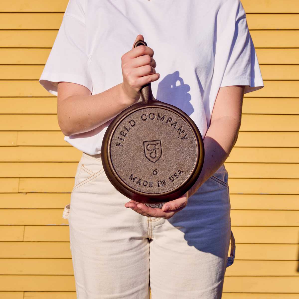 Black cast iron skillet held up, showing circular base logo