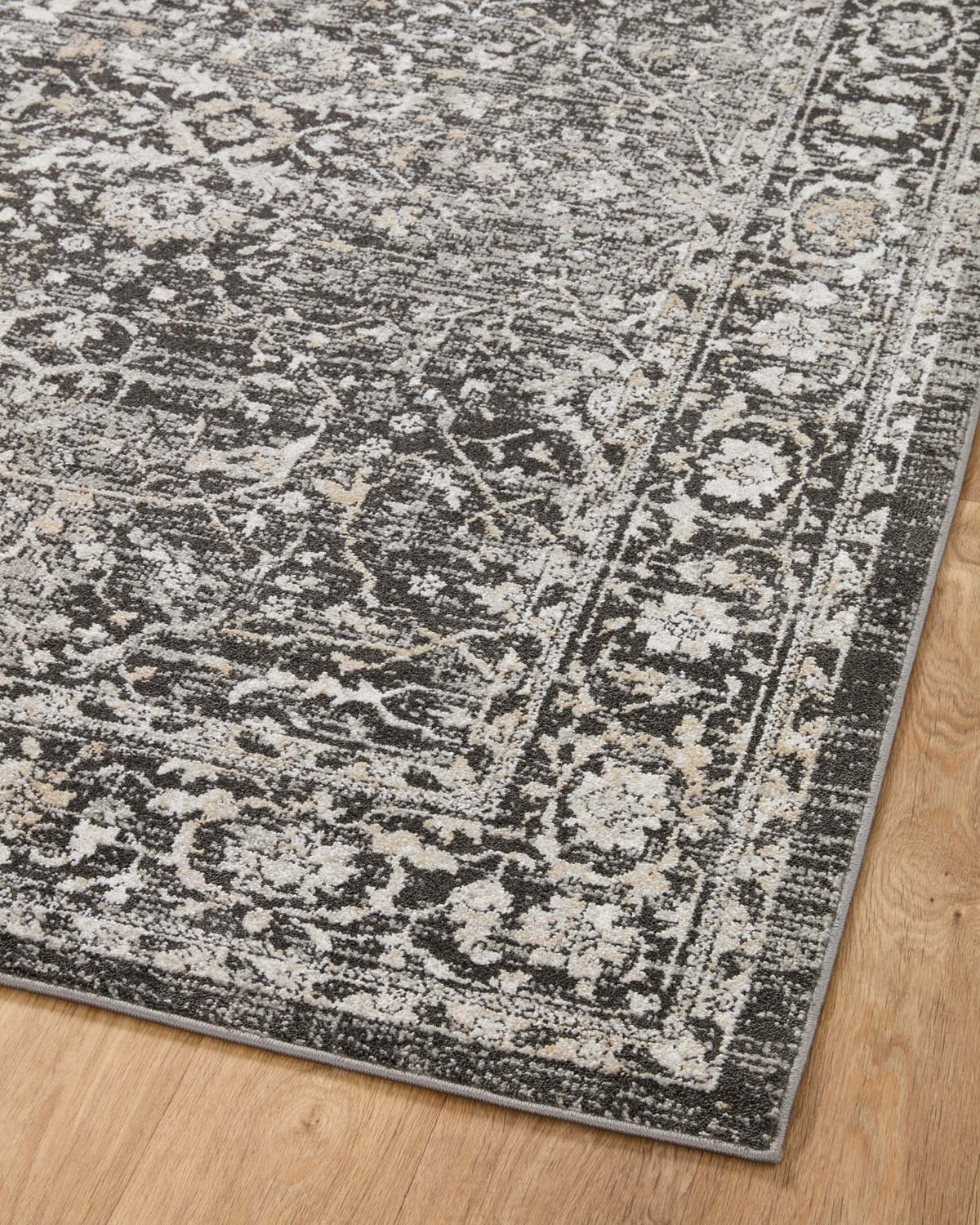 Charcoal-and-silver distressed traditional rug with intricate linework and border