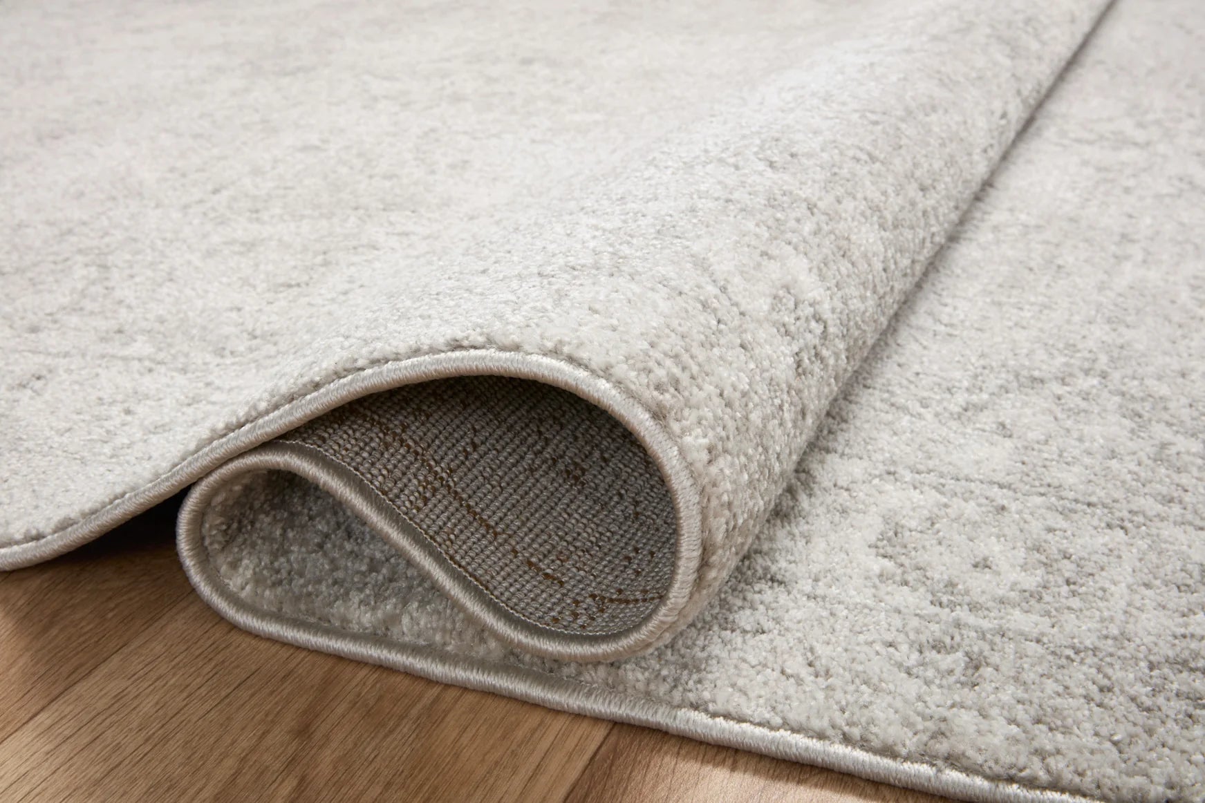 Close-up of silver and ivory runner rug edge with bound border and textured pile.