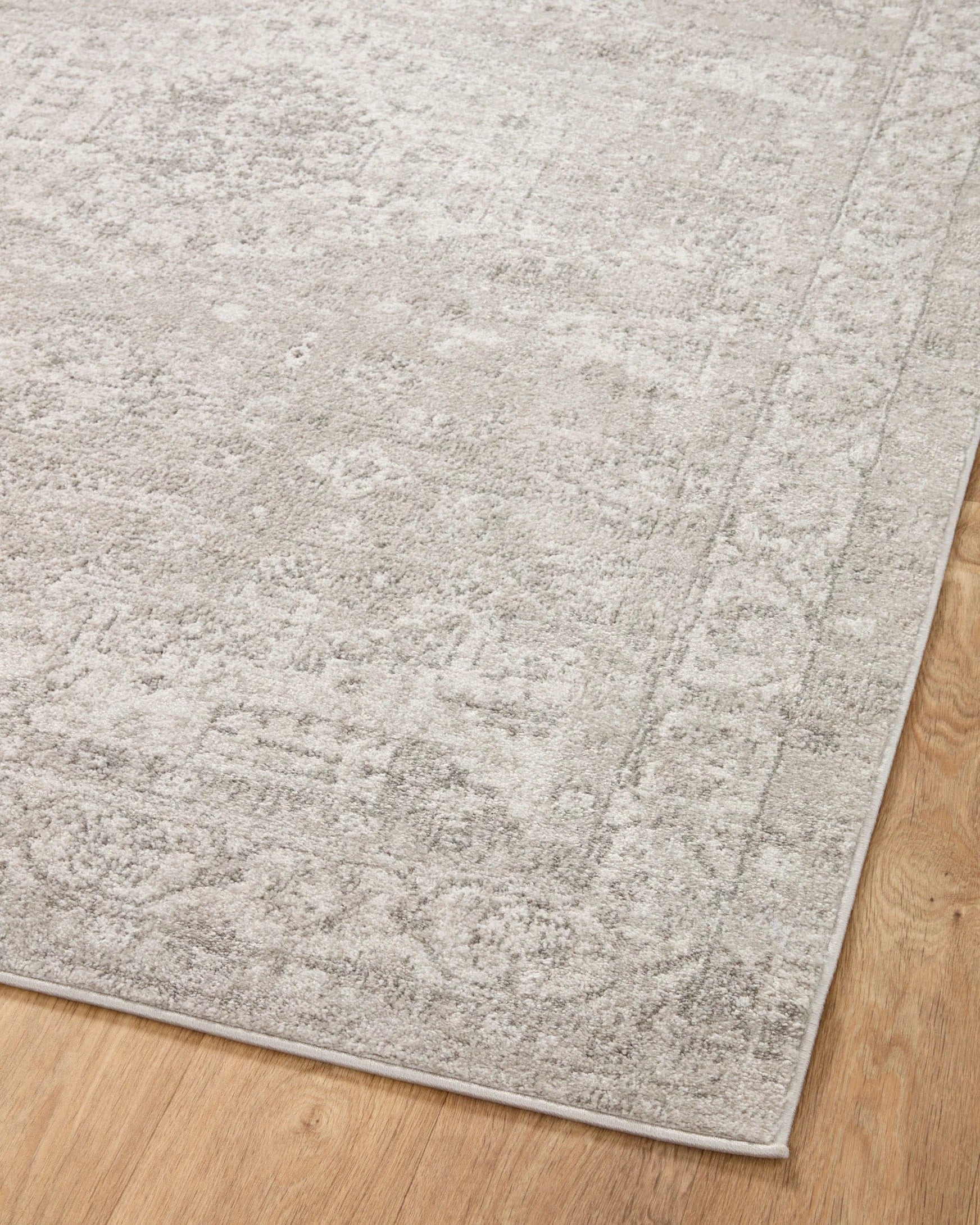 Silver and ivory runner rug corner with distressed texture and flat low pile.