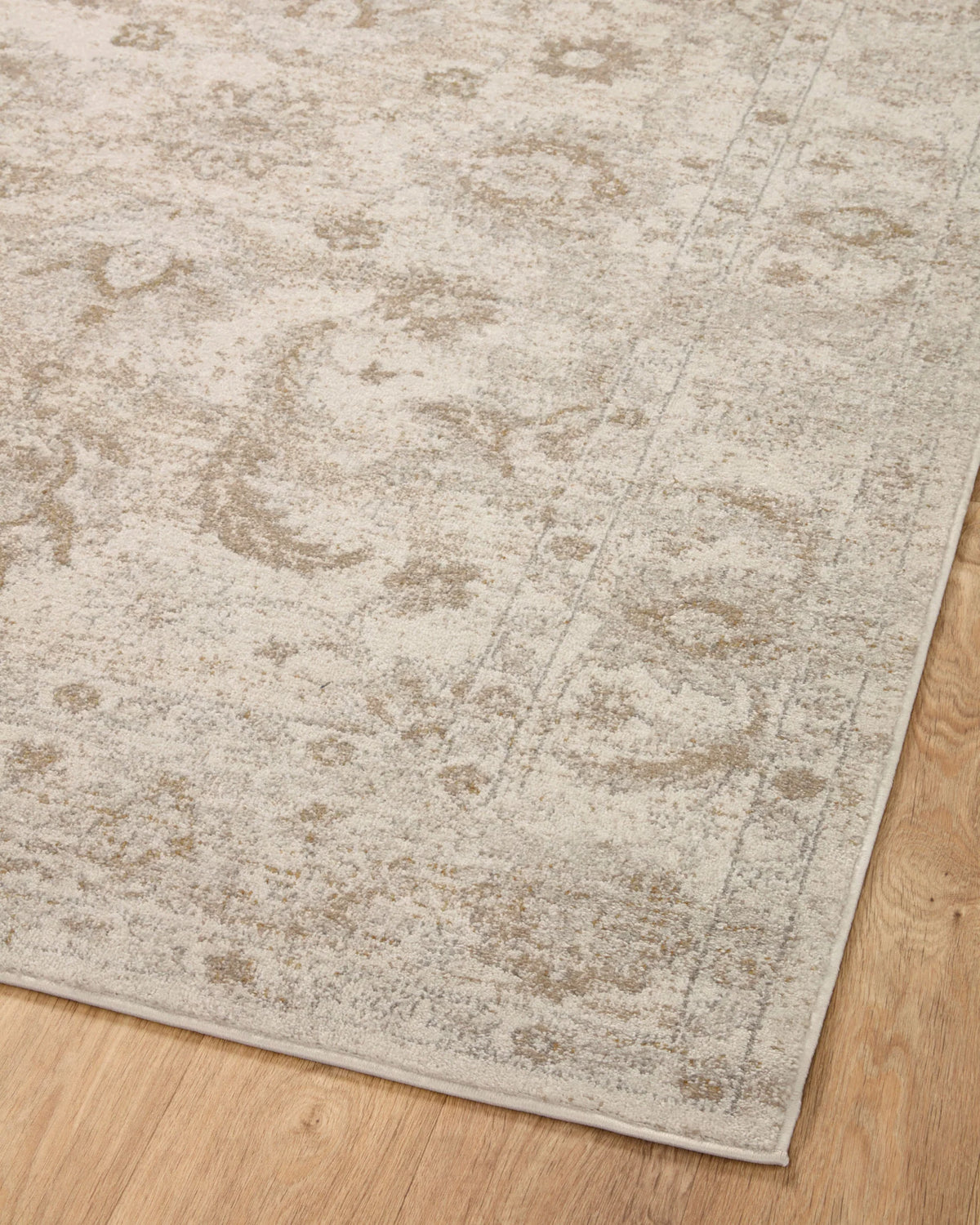 Ivory and beige traditional area rug with distressed motif and border at corner