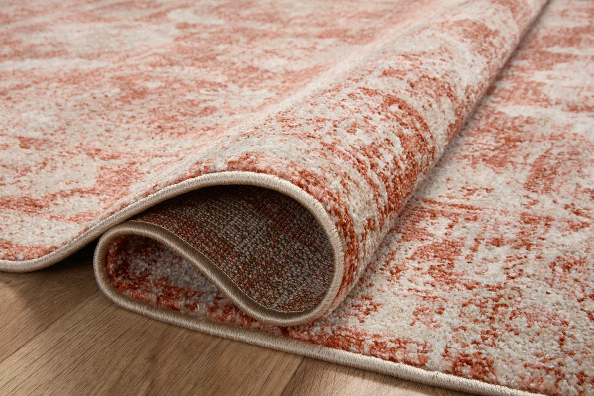 Rust and ivory area rug with bound edge and textured underside on wood flooring