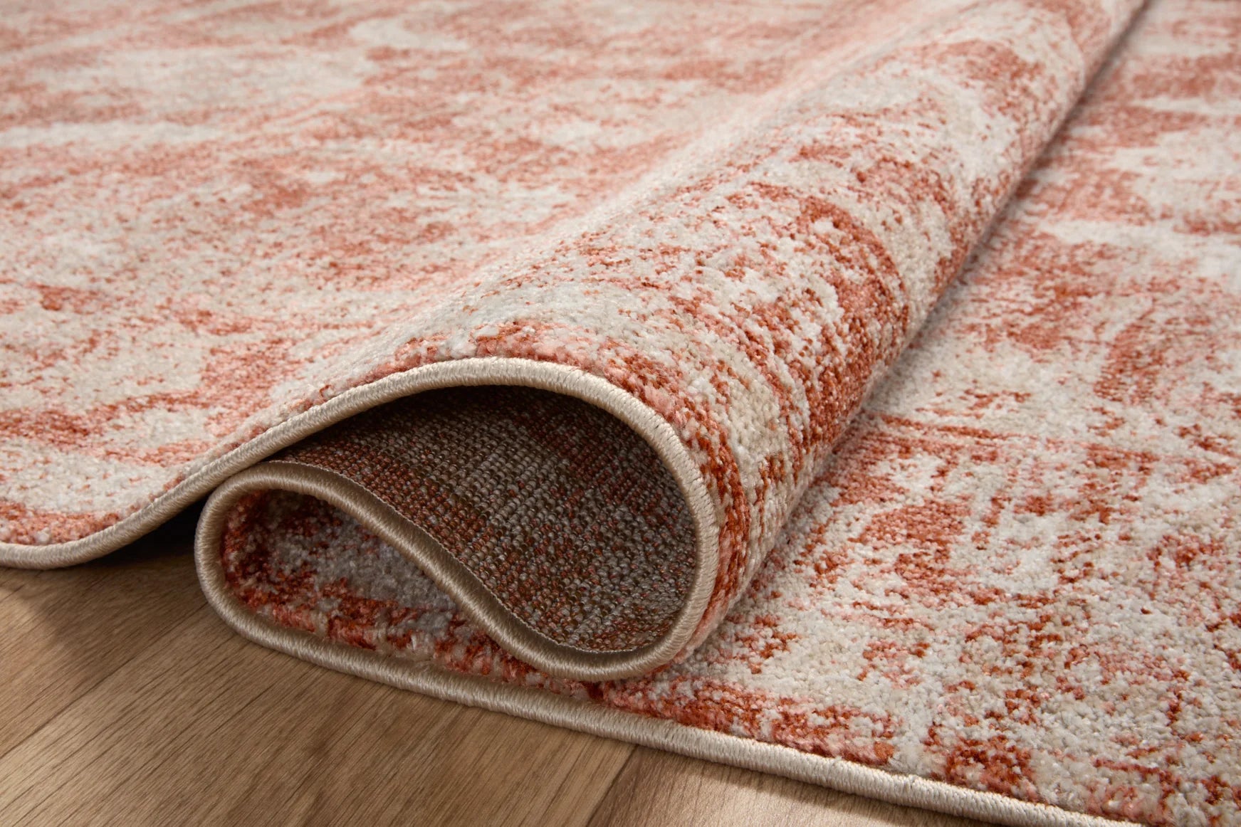 Rust and ivory area rug corner close-up with light border and textured pile.